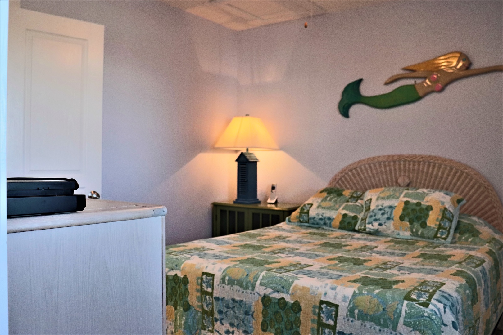 Your cozy bedroom features a comfortable bed with cheerful linens, warm lighting, and charming nautical touches that create a welcoming retreat.