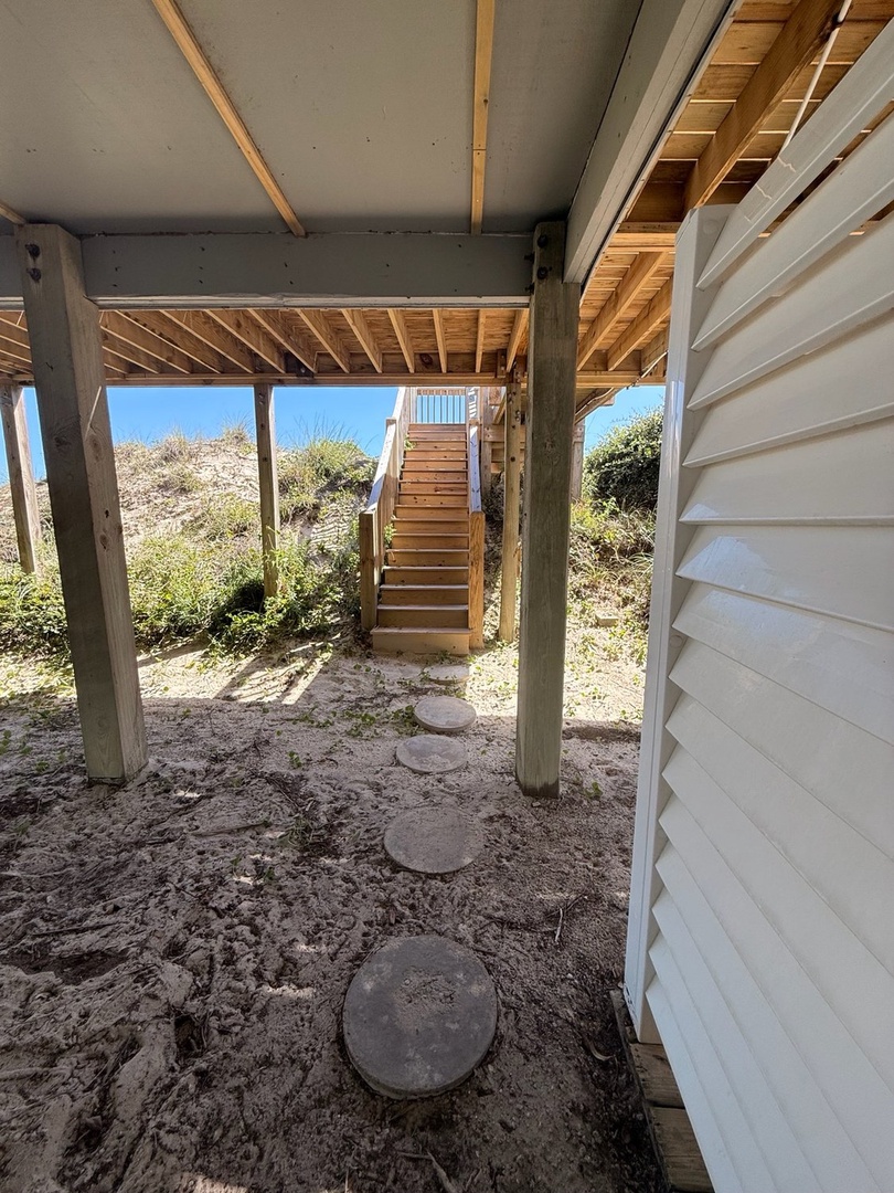 This ground-level space beneath the property opens to natural dunes and coastal vegetation, perfect for storing beach gear or sandy sandals before heading upstairs.