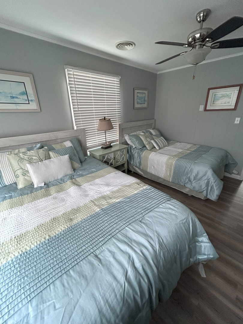 Unwind in this serene twin bedroom with coastal-inspired décor, crisp linens, and gentle ceiling fan for your perfect night's rest.