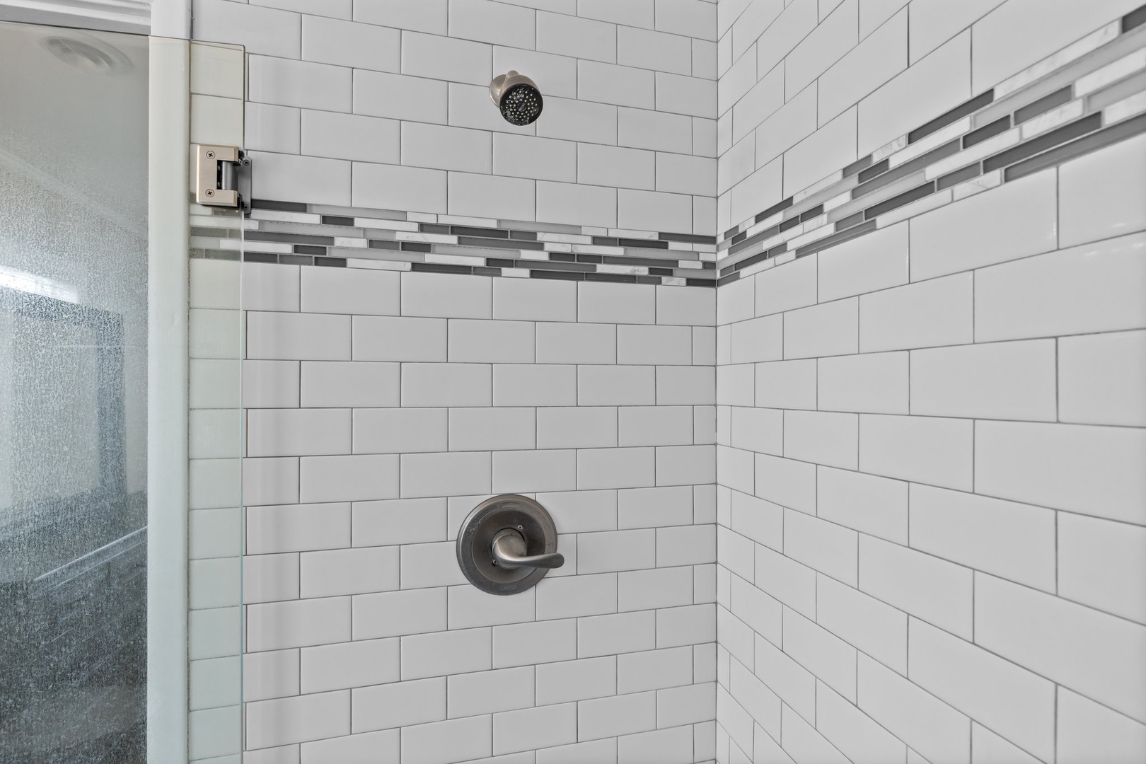 Step into your private spa-like shower featuring elegant subway tiles and stylish accent borders that create a refreshing retreat.