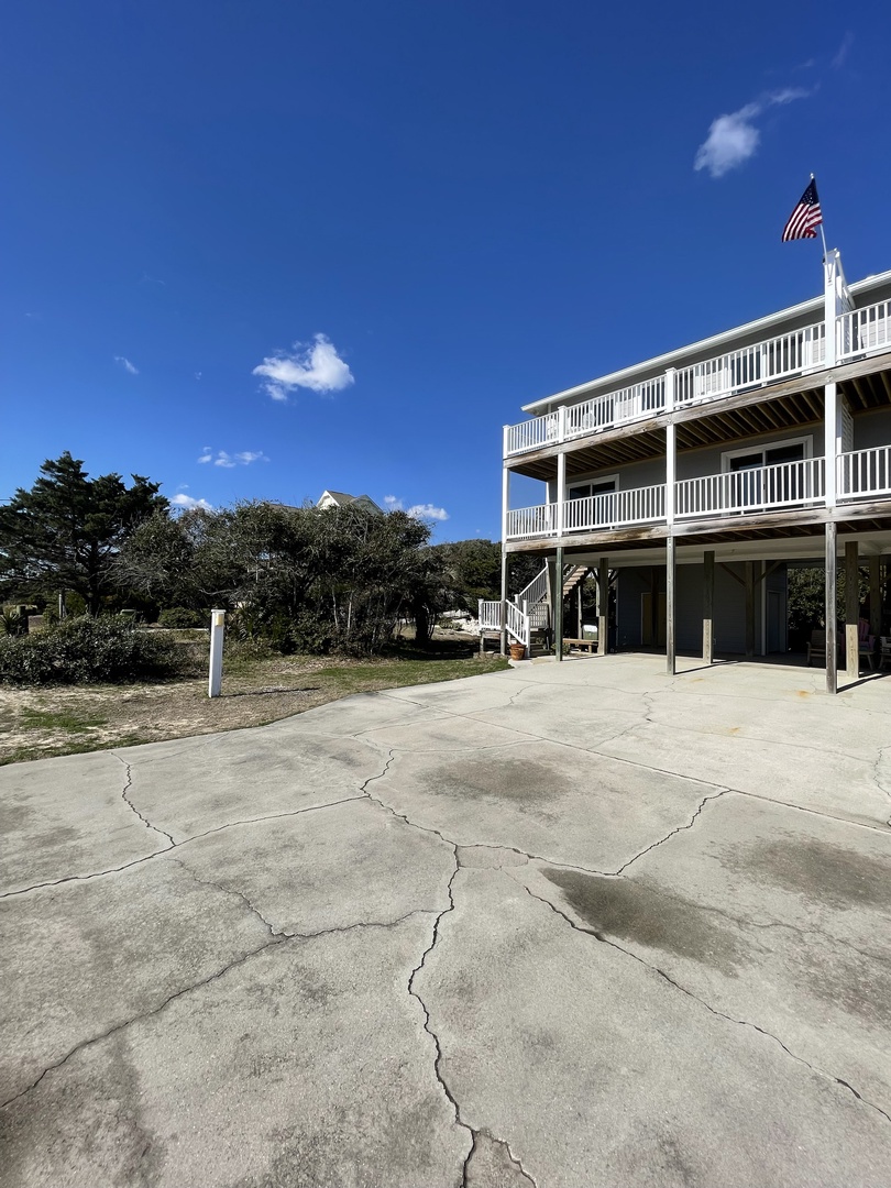 White colonial building with American flag stands proudly against clear blue skies and natural surroundings.