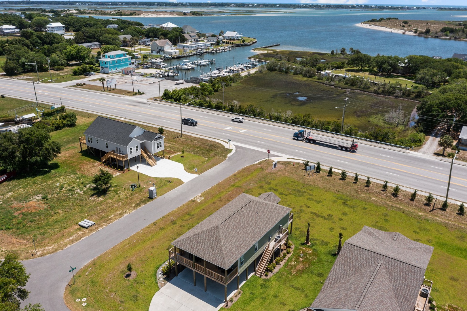 Aerial view of waterfront property featuring marina access, coastal homes, and scenic bay waters surrounded by lush greenery.