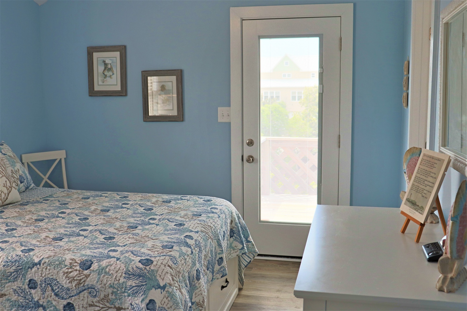 Wake up to sunshine streaming through your private door in this serene coastal bedroom with charming blue walls.