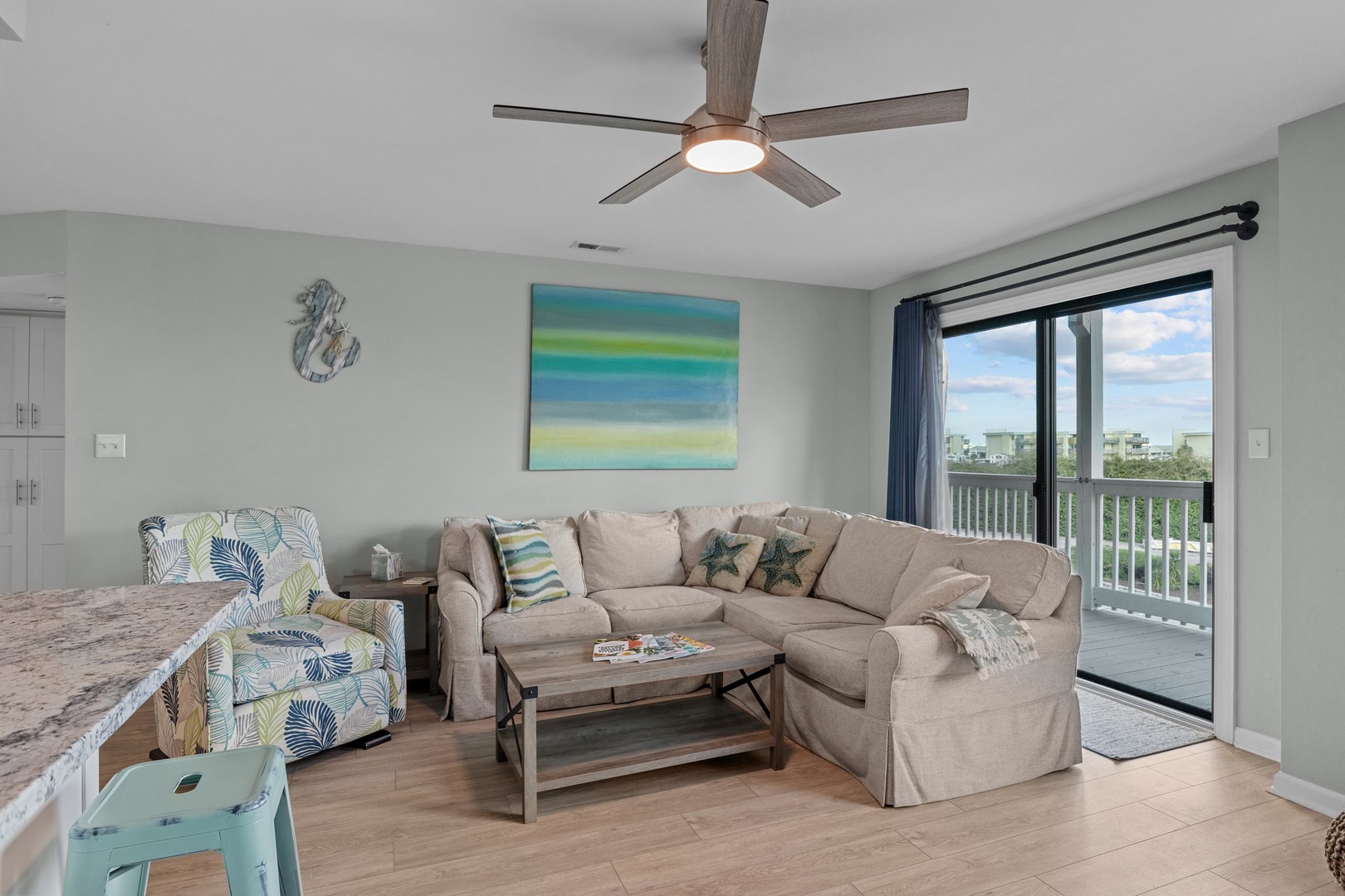 Relax in your coastal-themed living space with plush sectional seating, soothing ocean-inspired artwork, and private balcony access where gentle breezes flow through.