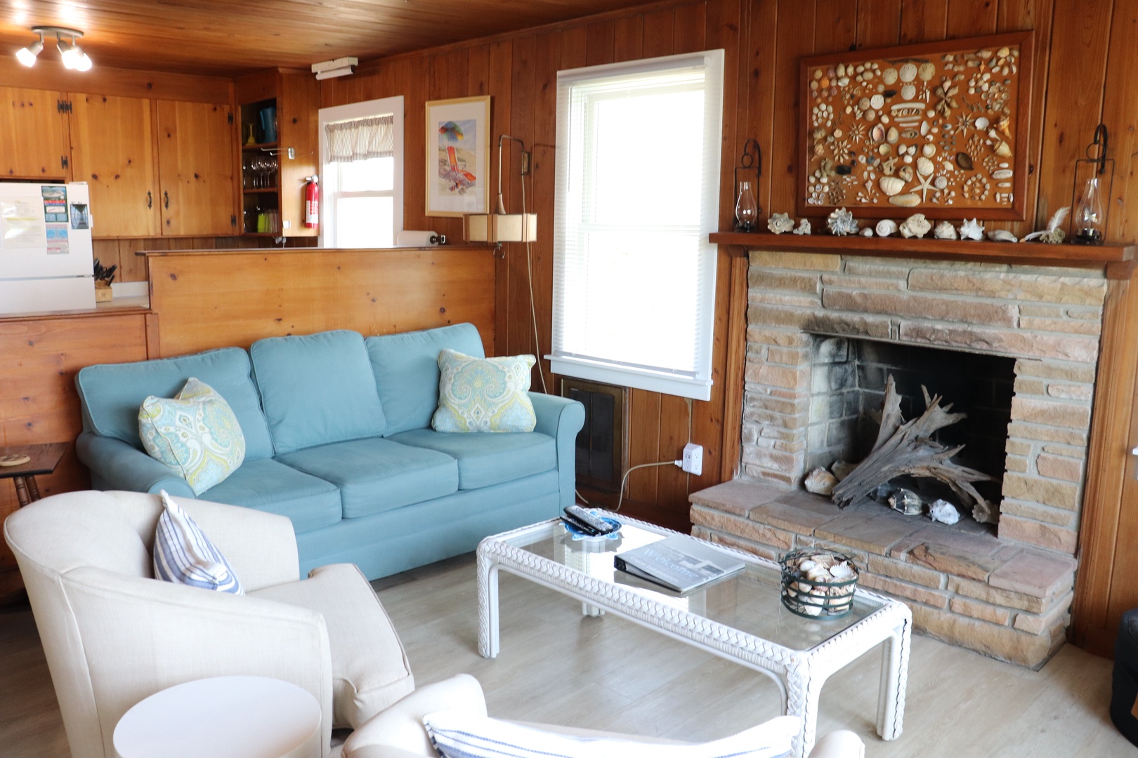 Cozy up in your warm wood-paneled living room with plush seating and a charming stone fireplace perfect for relaxing evenings.