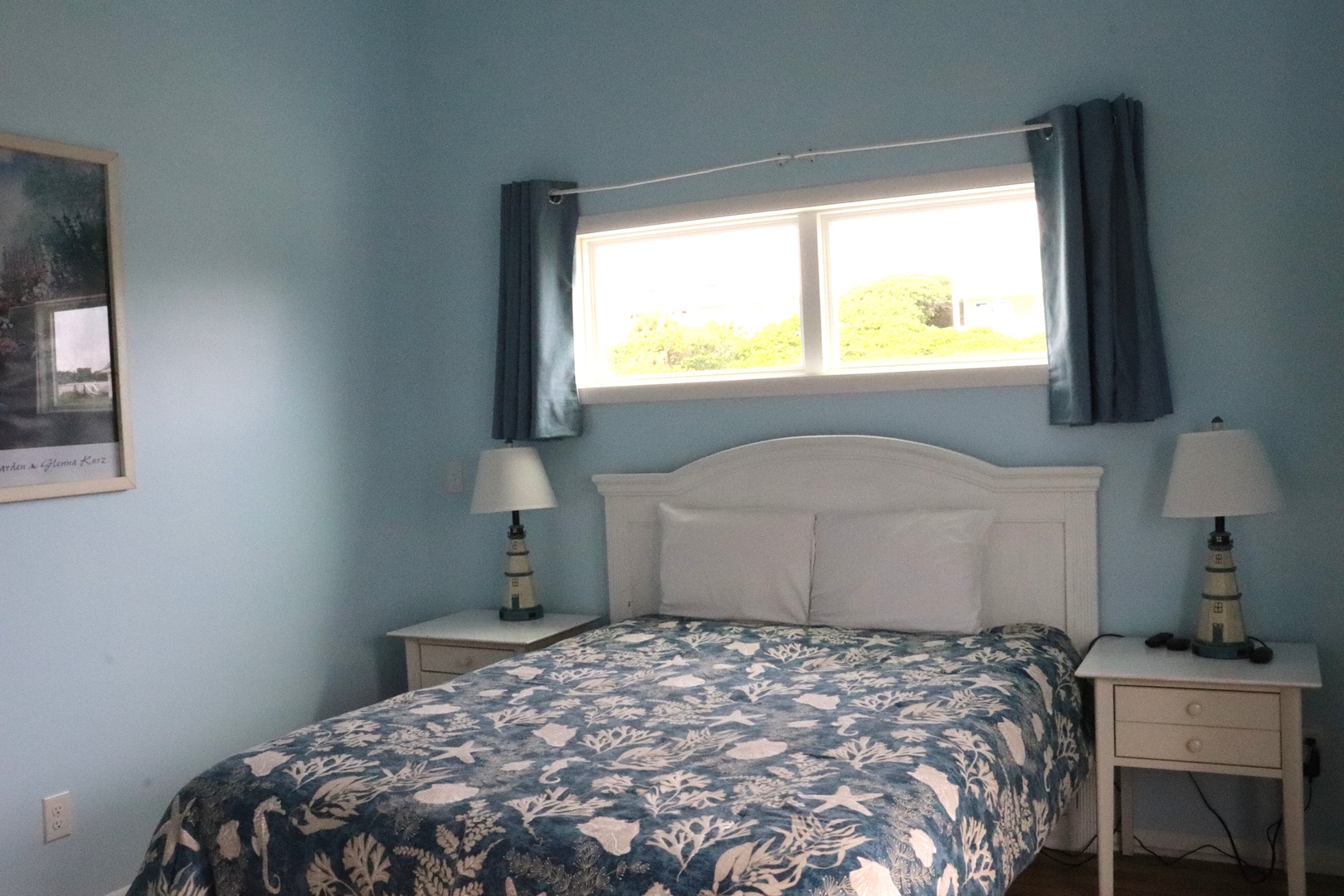 Wake up to calming coastal blues and bright green views through your window. Two cozy bedside lamps frame your comfortable bed, offering a restful retreat after island adventures.