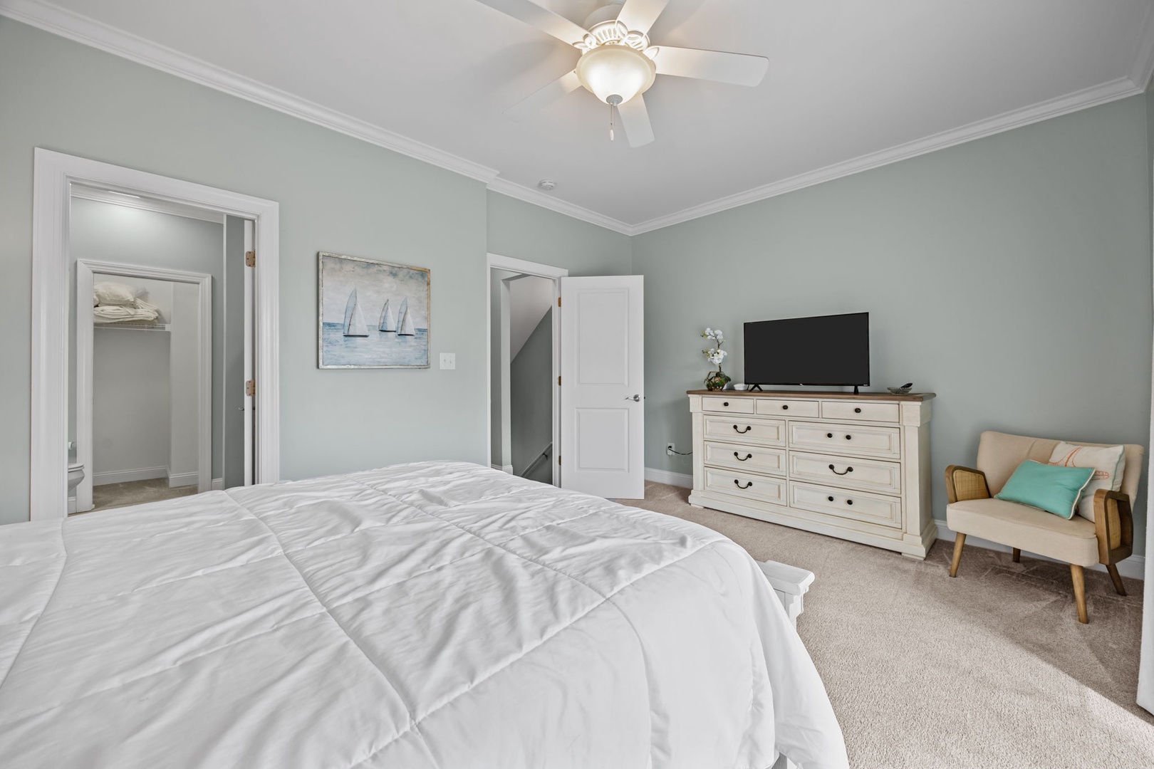 Unwind in your serene master bedroom, featuring plush bedding, modern TV, and a cozy reading nook perfect for morning coffee or evening relaxation.