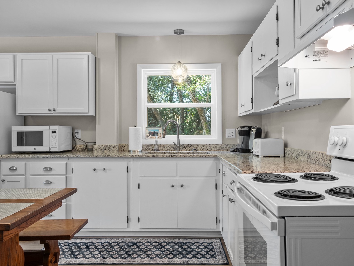 Step into your bright, fully-equipped kitchen featuring granite counters, modern appliances, and a peaceful garden view while you cook.