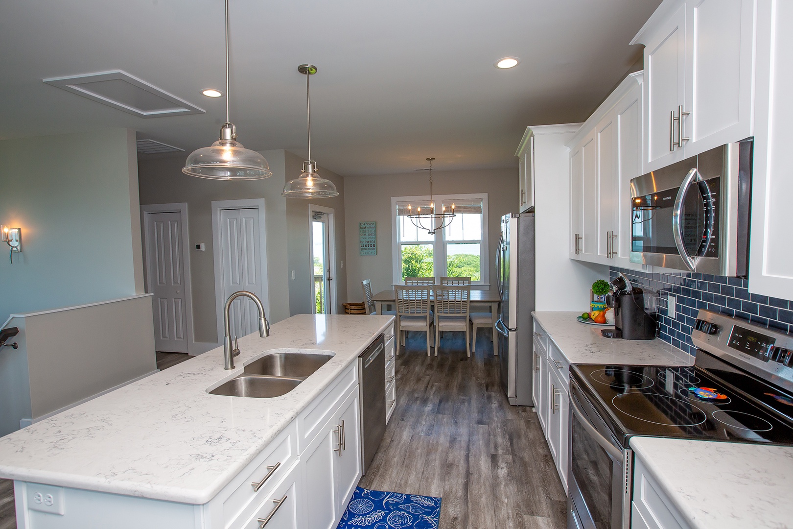 Your fully-equipped modern kitchen features pristine white cabinets, quartz countertops, and gleaming stainless appliances—perfect for preparing memorable meals during your stay.