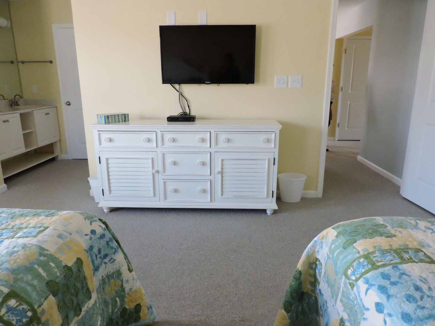 Your coastal-themed bedroom features twin beds with ocean-inspired linens and a white dresser beneath the wall-mounted TV for relaxing evenings.