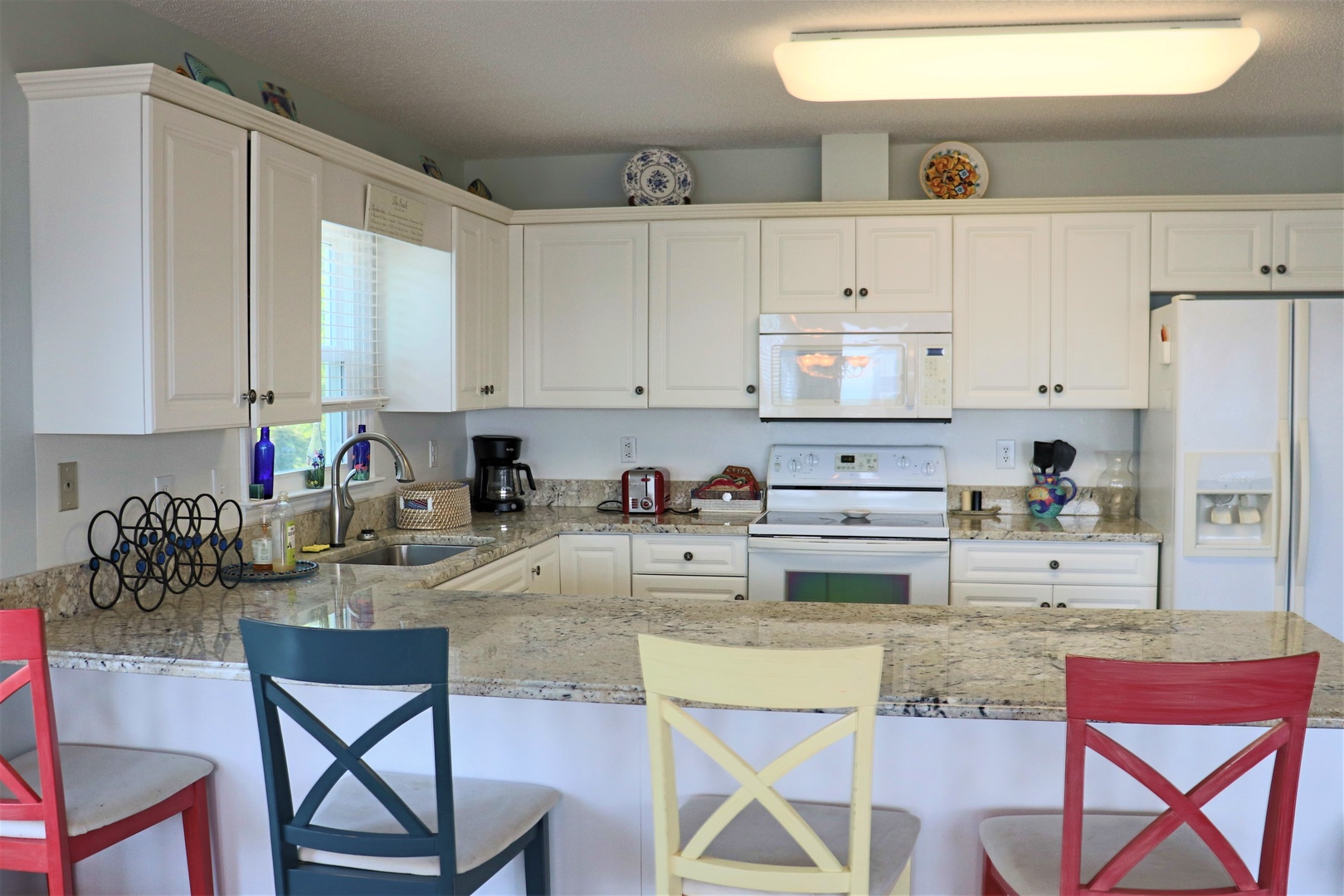 Your fully equipped kitchen awaits with granite counters and colorful seating—perfect for morning coffee or preparing meals together.