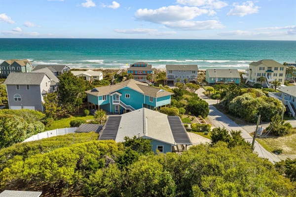 Coastal community with beach houses nestled among lush vegetation, offering direct access to pristine sandy shores and turquoise waters.