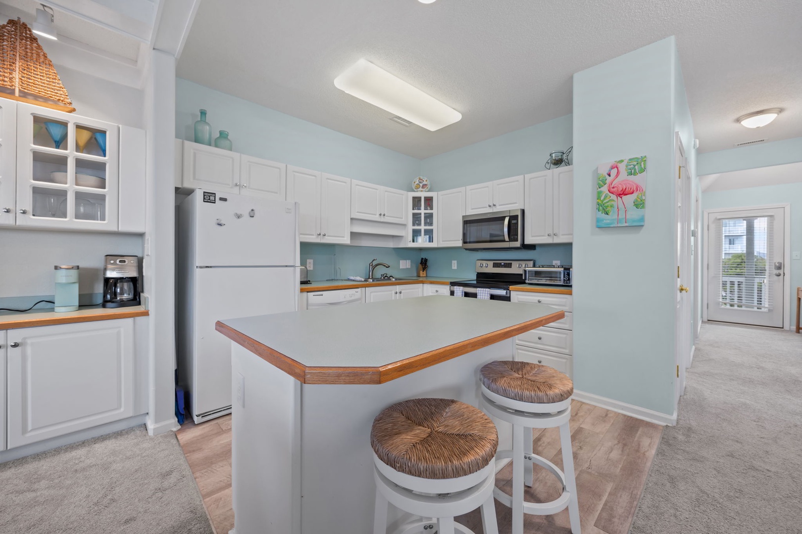Your bright kitchen features coastal blue walls, full appliances, and an island breakfast bar where you can start each morning with coffee.