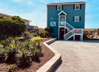 Your bright beachside retreat welcomes you with vibrant turquoise walls and tropical landscaping, creating the perfect coastal escape.