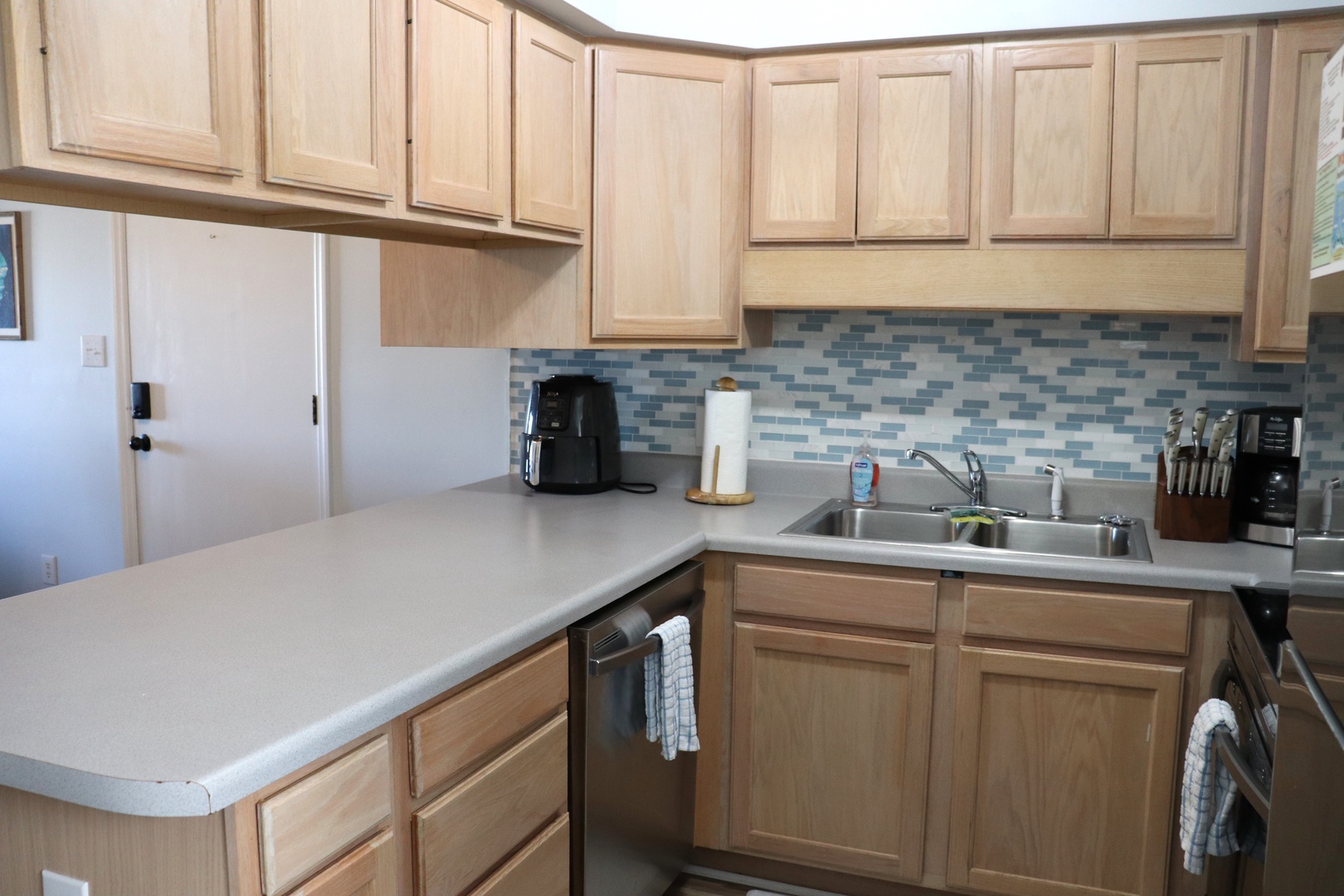 Your fully equipped kitchen features warm wood cabinets, modern appliances, and a charming blue mosaic backsplash for memorable home-cooked meals.