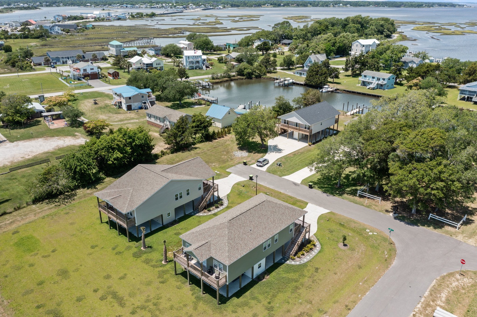 Aerial view of waterfront vacation rental community with canal access, boat docks, and coastal marsh landscapes nearby.