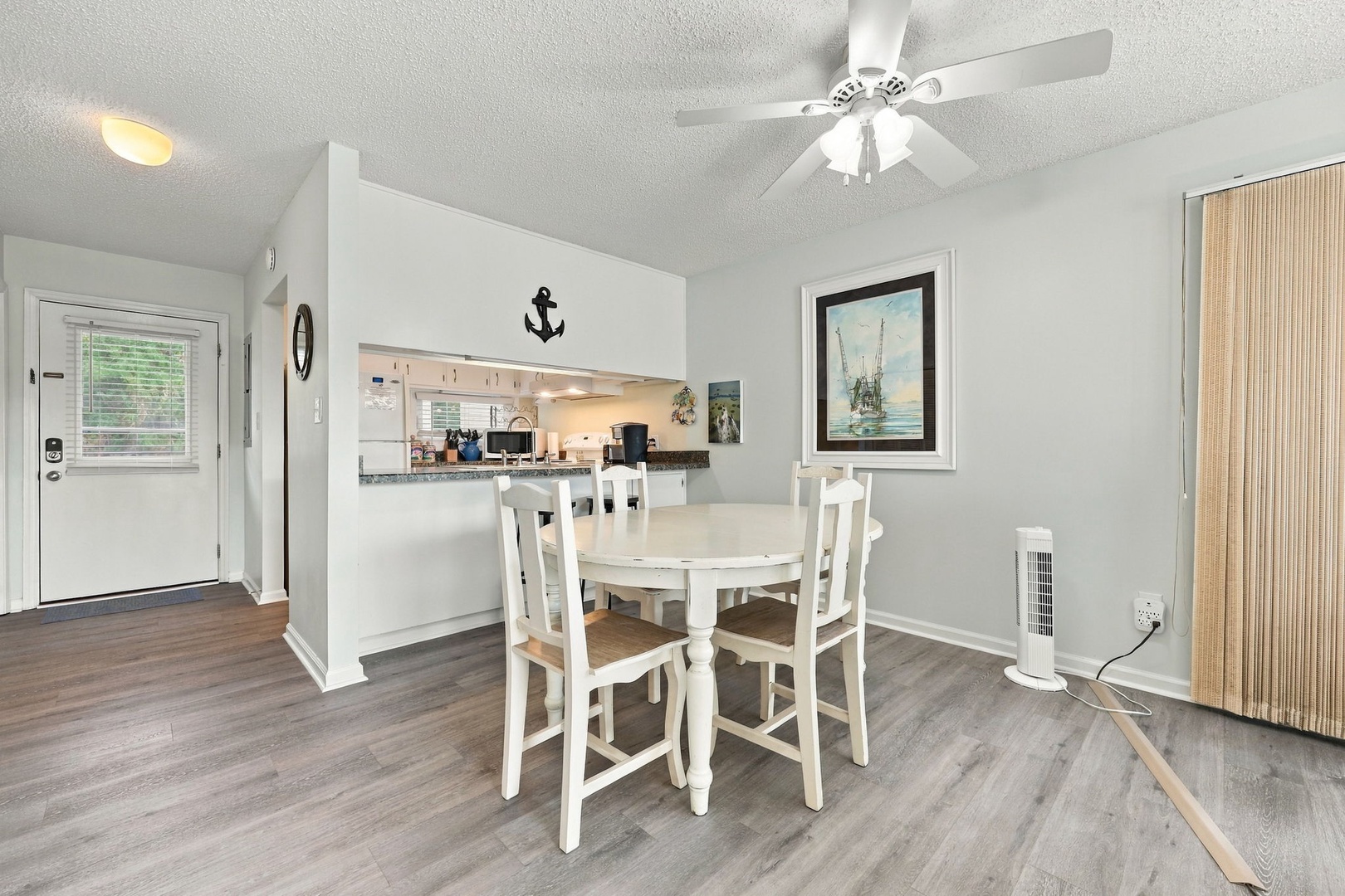 Your bright dining space flows seamlessly into the kitchen, creating an inviting atmosphere for meals together. A ceiling fan keeps you comfortable, while coastal-inspired décor brings relaxed charm to your vacation retreat.