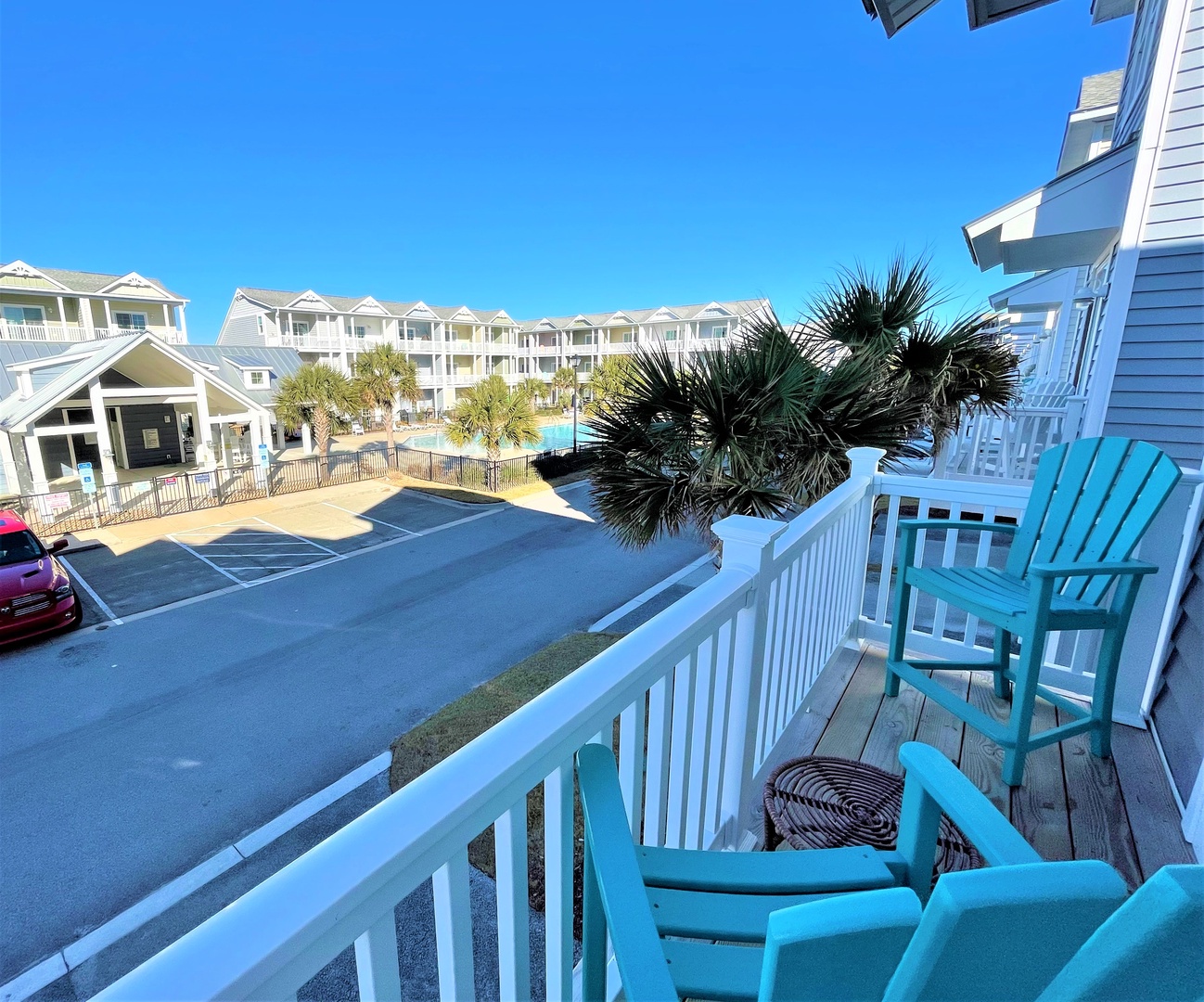 Relax on your private balcony with turquoise Adirondack chairs while enjoying views of the resort pool and tropical palms.