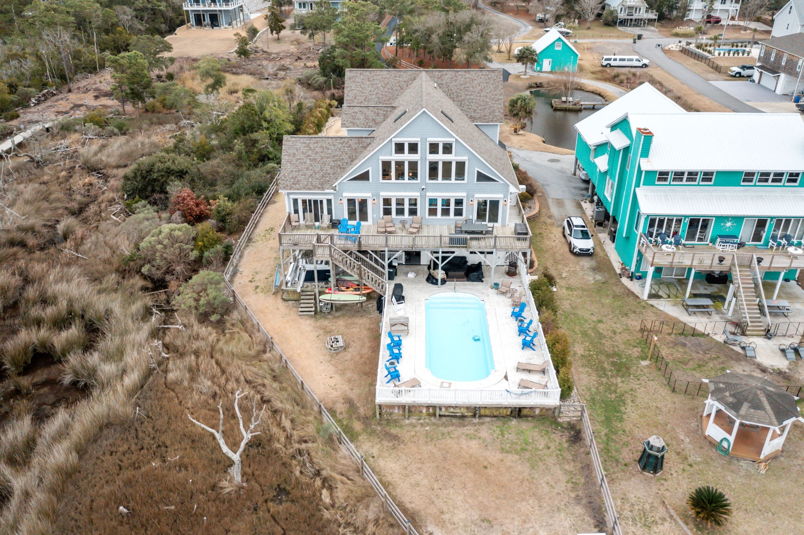 Aerial view of the coastal vacation rental featuring a private swimming pool surrounded by neighboring beach houses in this peaceful residential area.