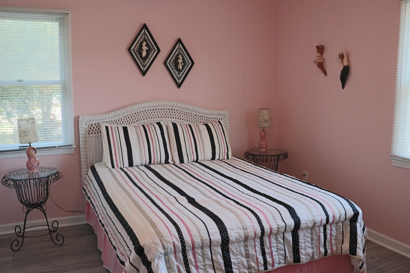 Your charming bedroom features soft pink walls and natural light streaming through windows, creating a cozy retreat for peaceful nights.