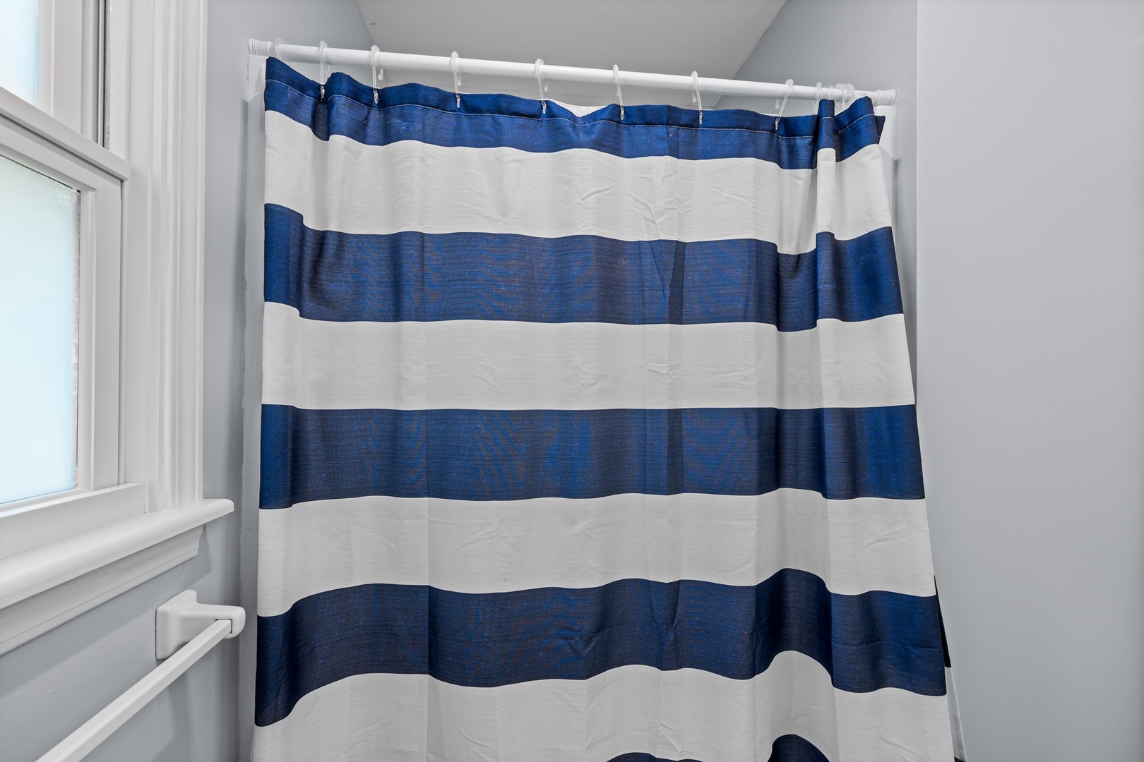 Step into your private bathroom with a classic blue and white striped shower curtain adding nautical charm to your refreshing morning routine.