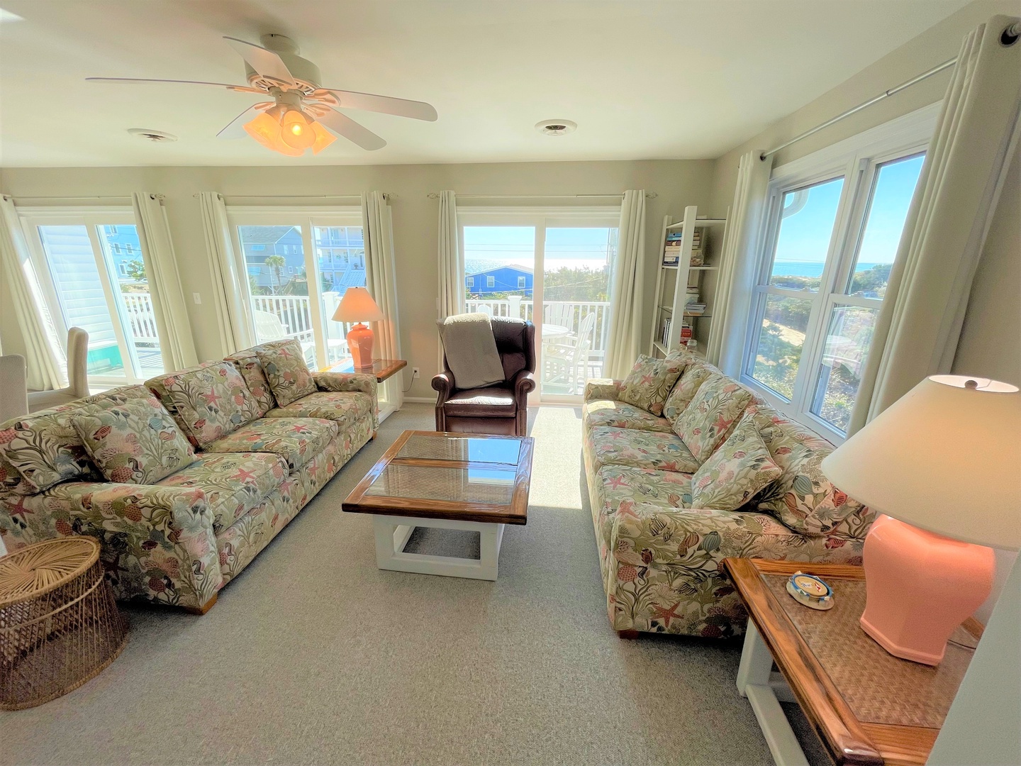 Unwind in your bright living room with tropical sofas and stunning ocean views through floor-to-ceiling windows.