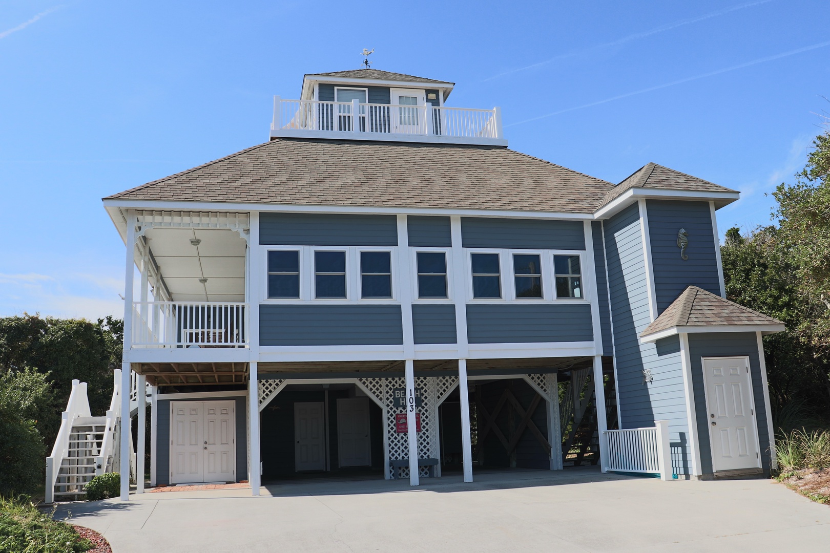 Coastal vacation home with distinctive observation deck and wraparound balcony, featuring elevated design and ample parking space.