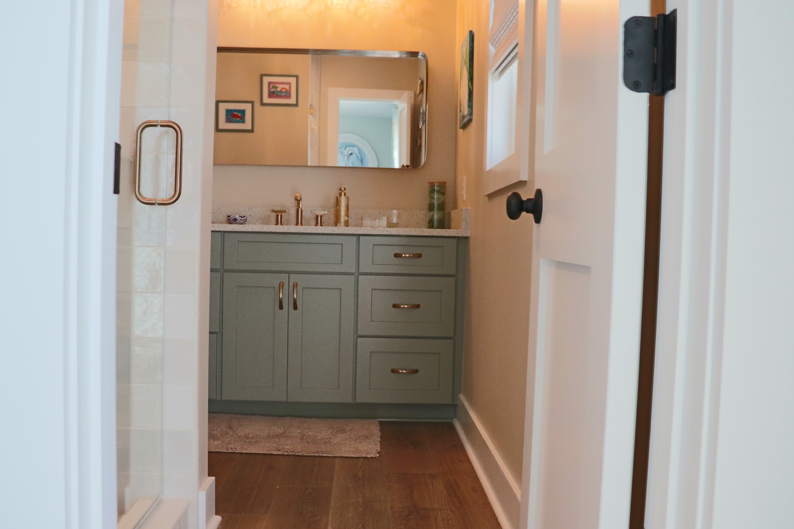 Step into your stylishly appointed bathroom featuring sage green cabinetry, brass fixtures, and thoughtful touches that create a spa-like retreat.