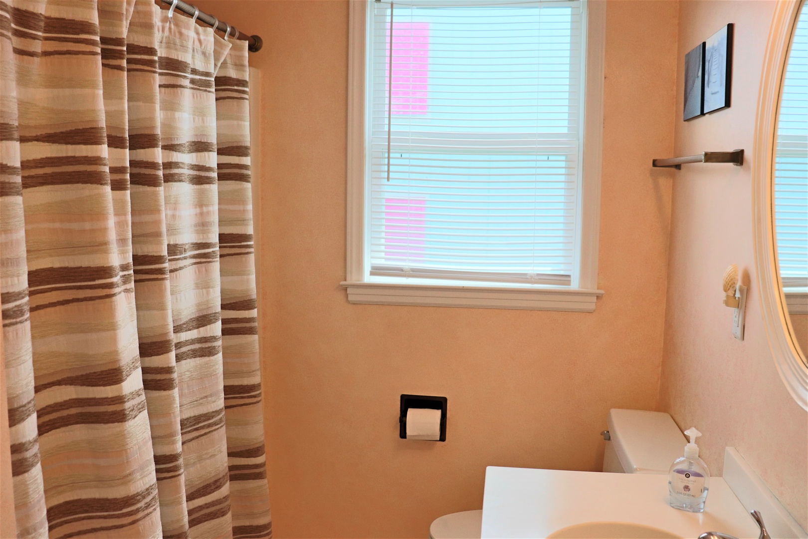 Step into your private bathroom featuring a refreshing shower with stylish striped curtains and natural light streaming through the window.