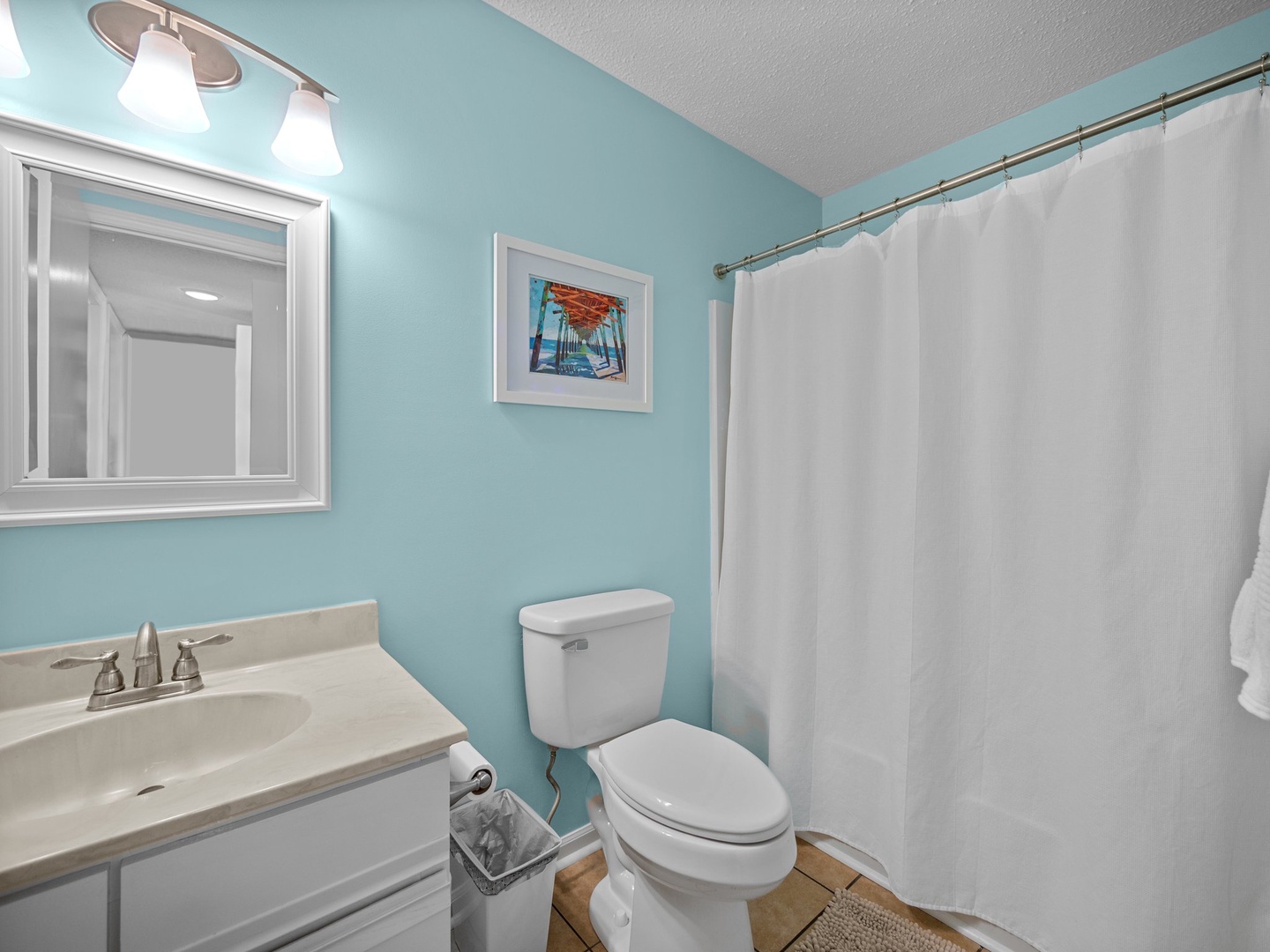 Refresh in your bright, coastal-themed bathroom featuring calming turquoise walls, modern fixtures, and a spacious shower area.