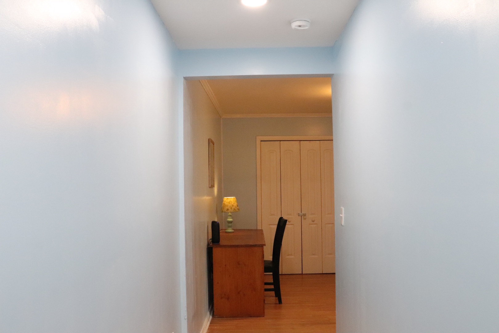 Your private hallway opens to a cozy space with warm wood floors and a desk tucked beside built-in closets—perfect for unwinding or catching up.