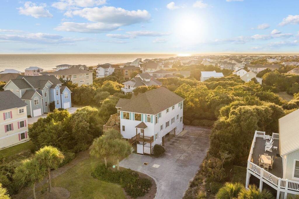 Coastal community with beach homes nestled among lush trees, just steps from the sandy shoreline and ocean.
