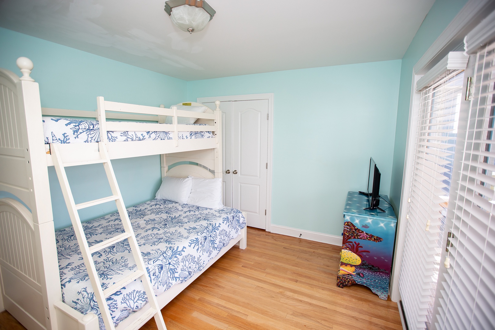 Your kids will love this cheerful aqua bedroom with cozy bunk beds and their own TV for movie nights.