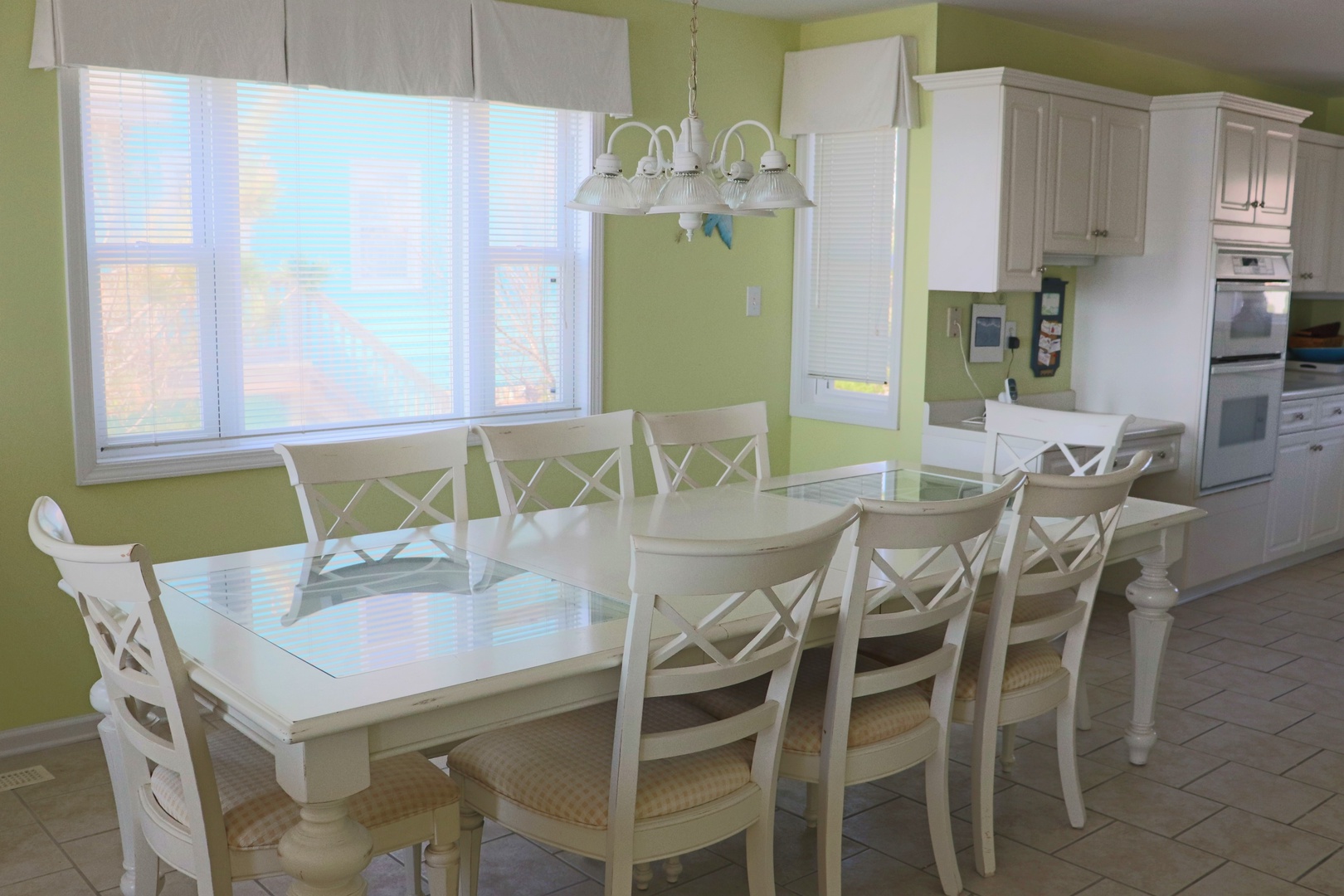 Bright dining space with large table for memorable meals together, overlooking peaceful views through expansive windows.