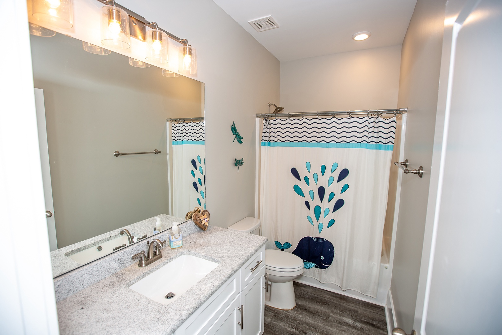 Refresh in your bright bathroom featuring playful whale-themed decor, modern vanity lighting, and granite countertops for a delightful start to each day.