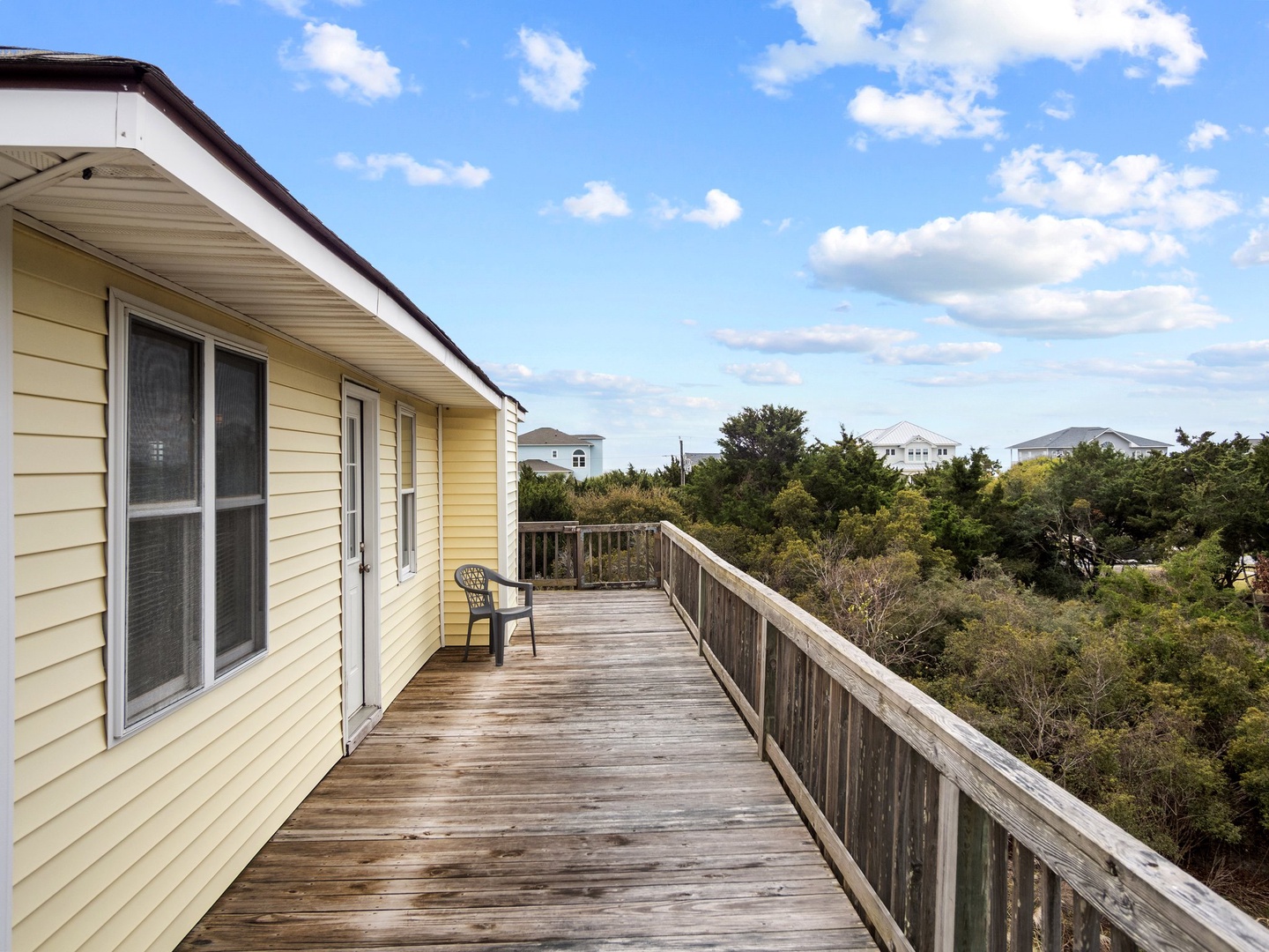 Step onto your private deck and breathe in the fresh coastal air, where treetop views and neighboring beach homes create a serene escape.