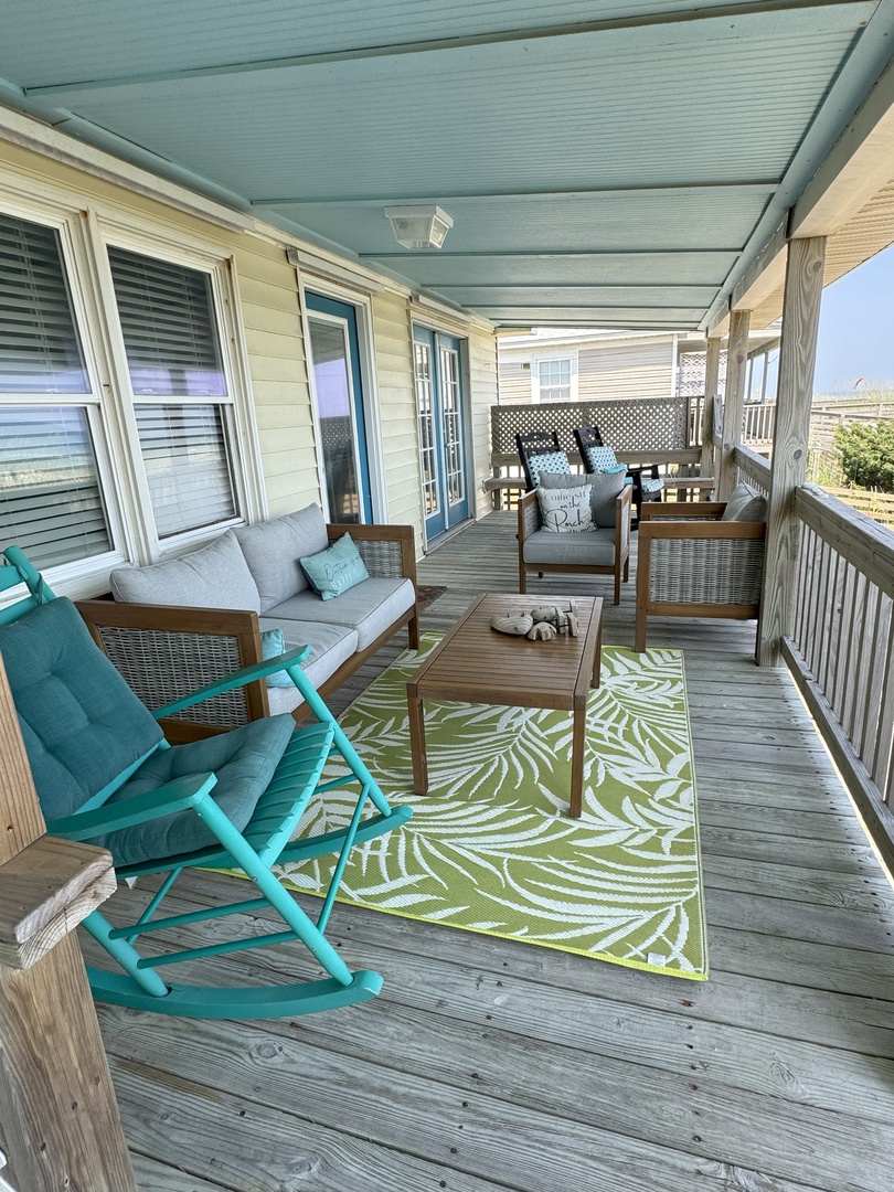 Your covered porch offers the perfect retreat with cozy seating, tropical decor, and gentle ocean breezes for morning coffee or sunset relaxation.