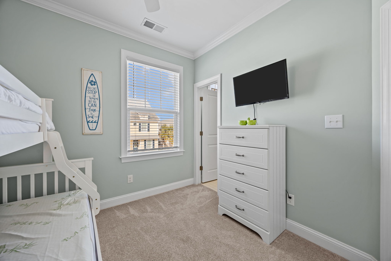 Your kids will love this cheerful bunk room with soft mint walls, plenty of storage, and their own TV for movie nights.