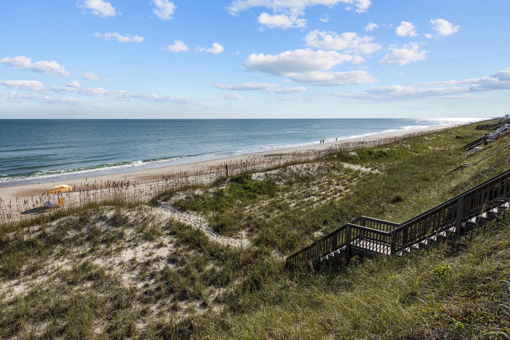 Pristine beachfront stretches endlessly with convenient boardwalk access leading down to the sandy shore and sparkling ocean waves.