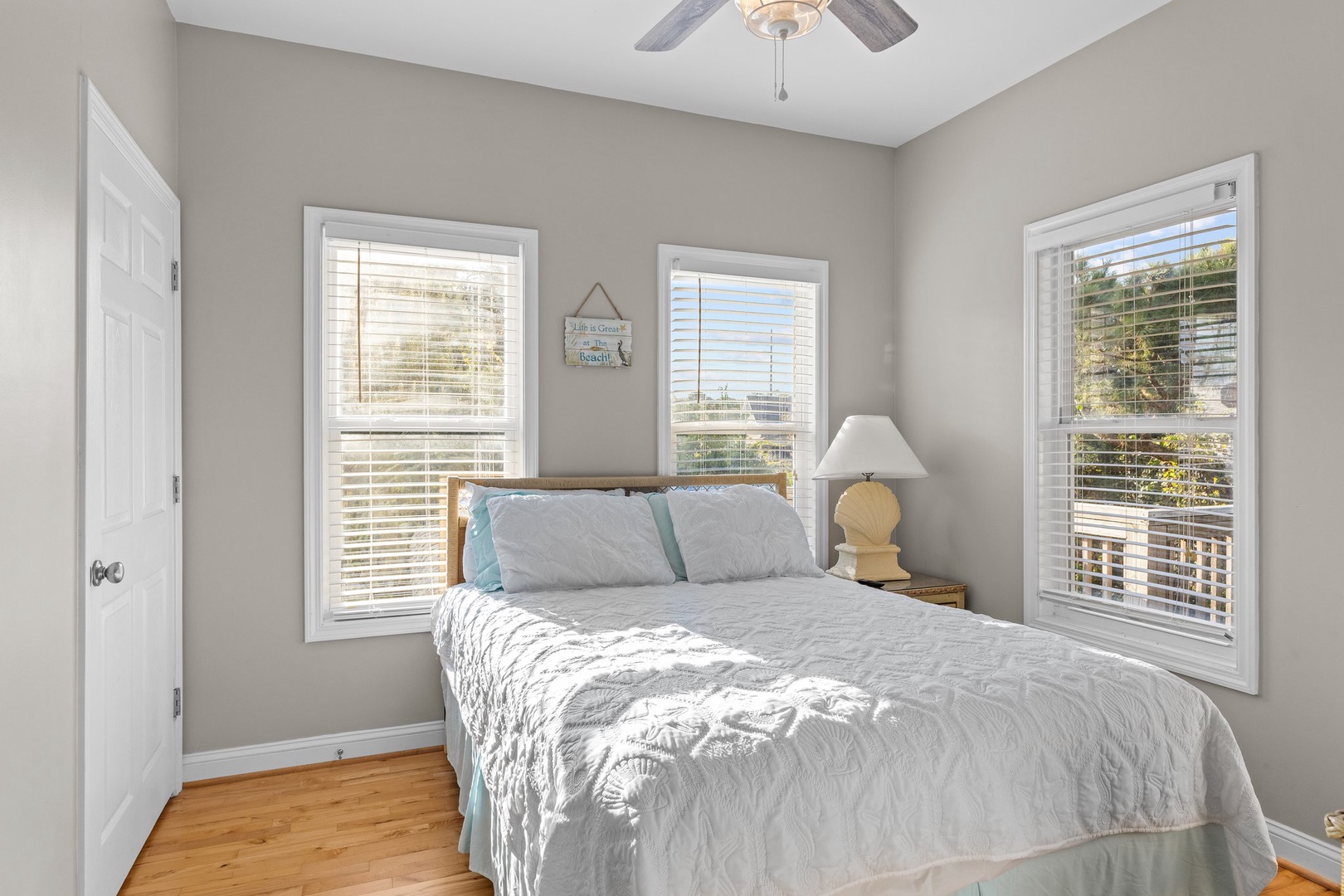 Drift off peacefully in your bright, airy bedroom with soft coastal linens and gentle breezes from the ceiling fan overhead.