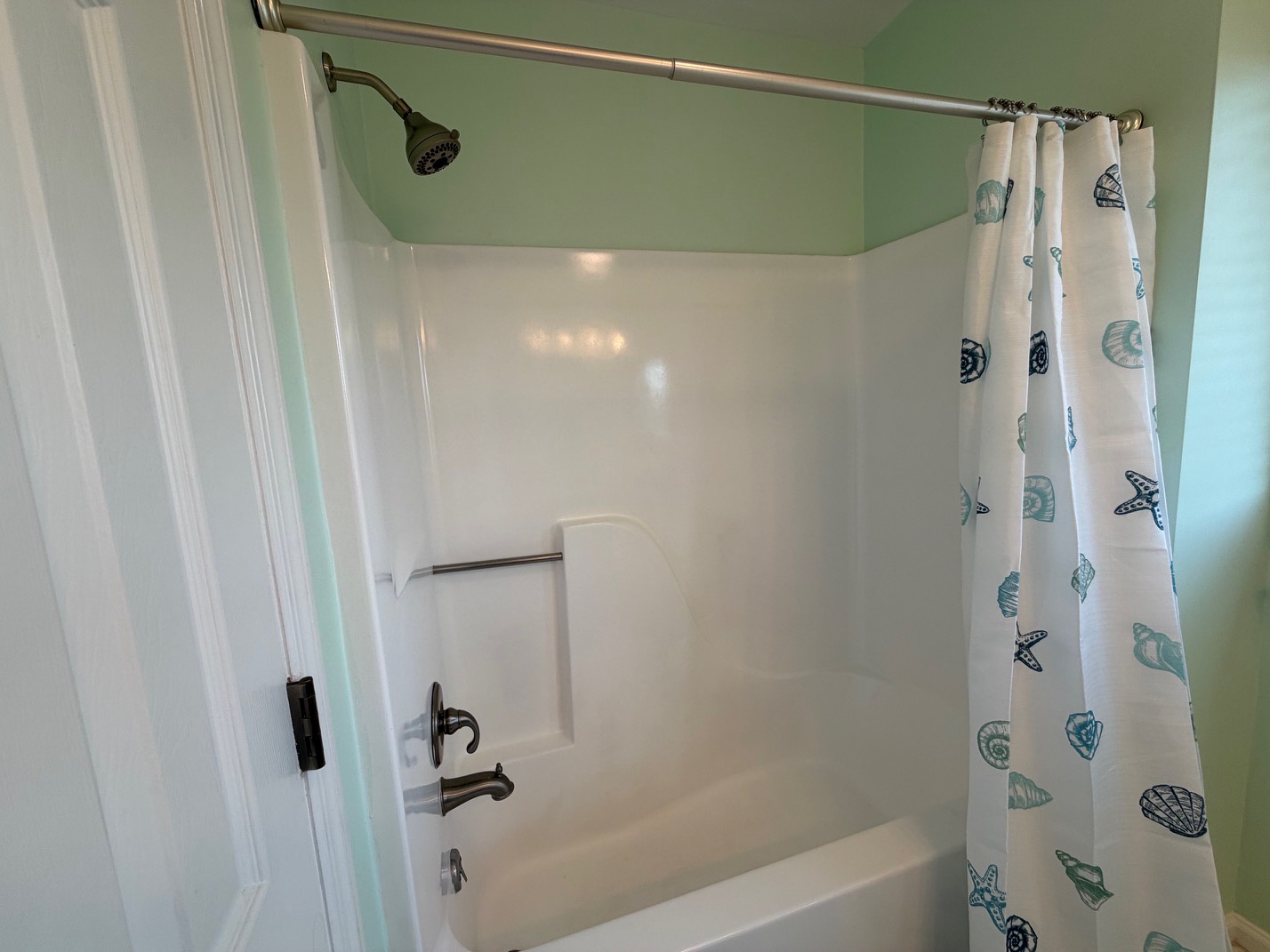 Your private bathroom features a spacious tub-shower combo with charming seashell curtains that add coastal flair to your relaxing retreat.