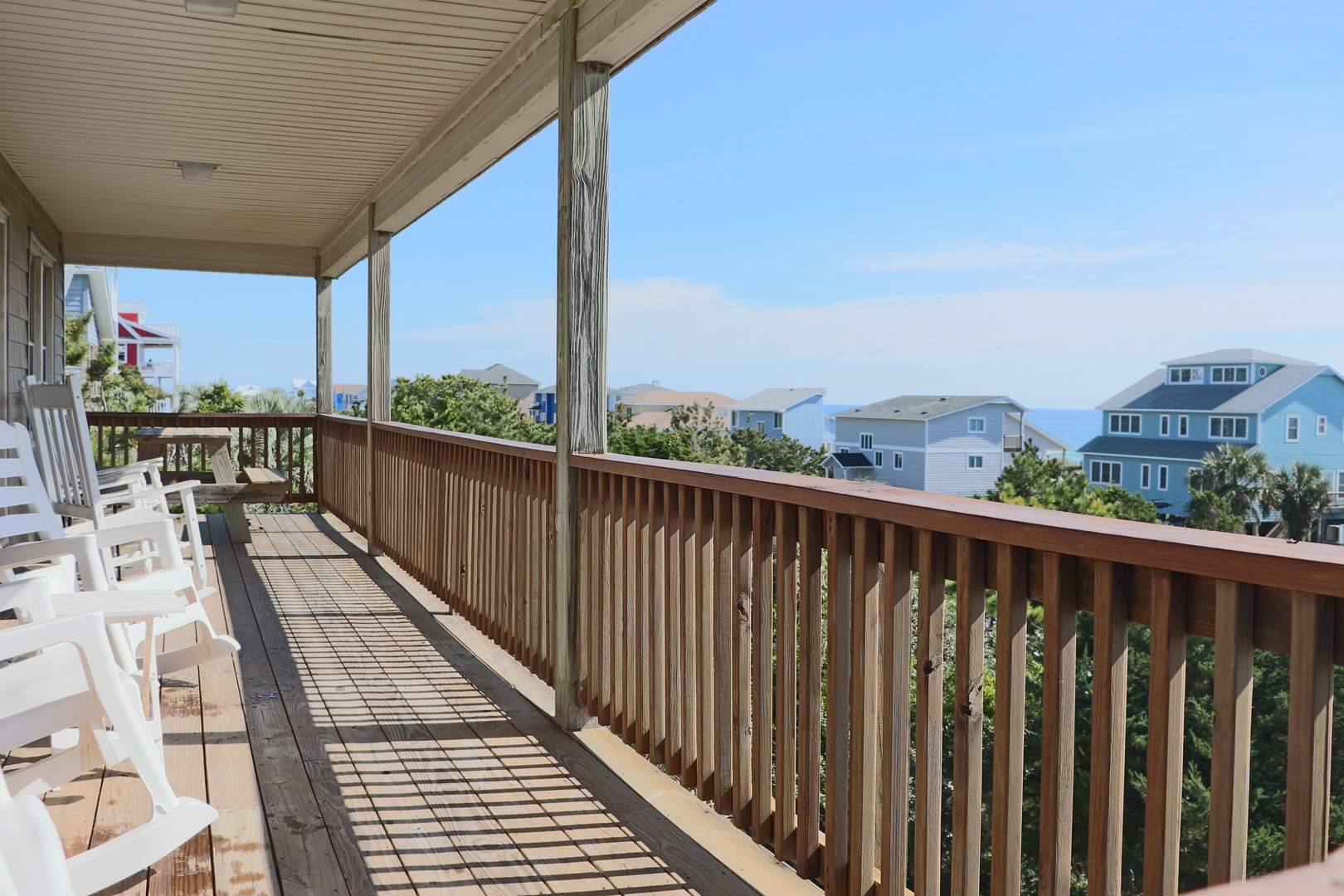 Relax in white chairs on your private balcony overlooking neighboring beach homes and distant ocean views.