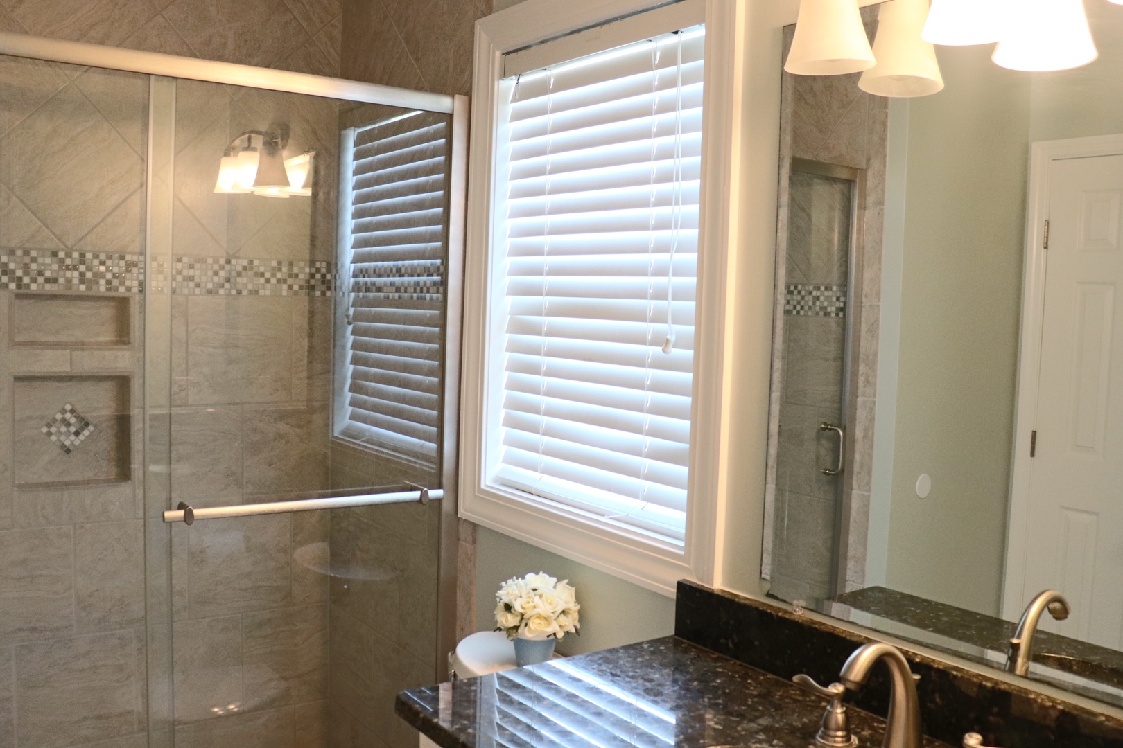 Step into your private spa-like bathroom featuring a luxurious glass shower with beautiful tilework and elegant granite countertops.