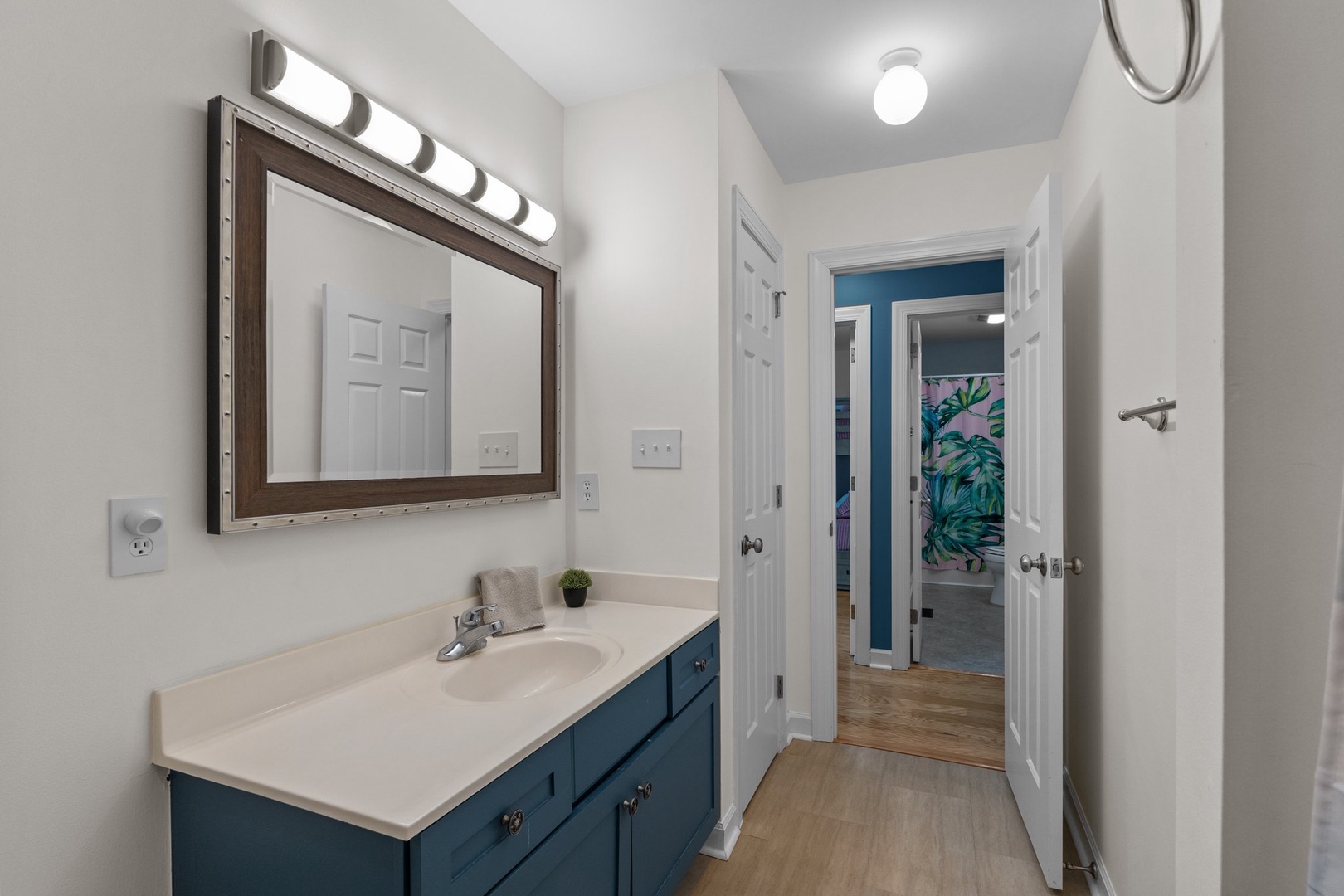 Your elegant bathroom features Hollywood-style vanity lighting and stylish blue cabinetry for a refreshing morning routine.
