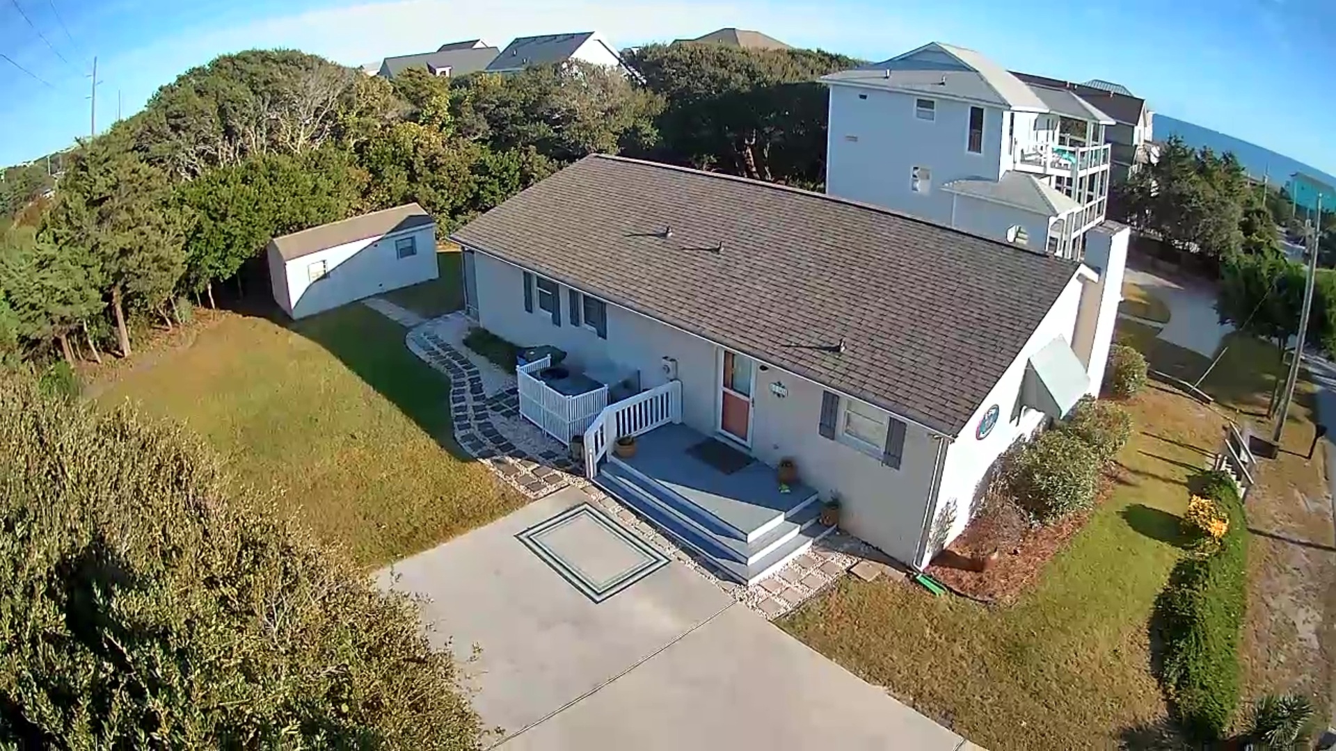 Coastal property surrounded by lush vegetation and neighboring homes, featuring spacious grounds and convenient parking area.