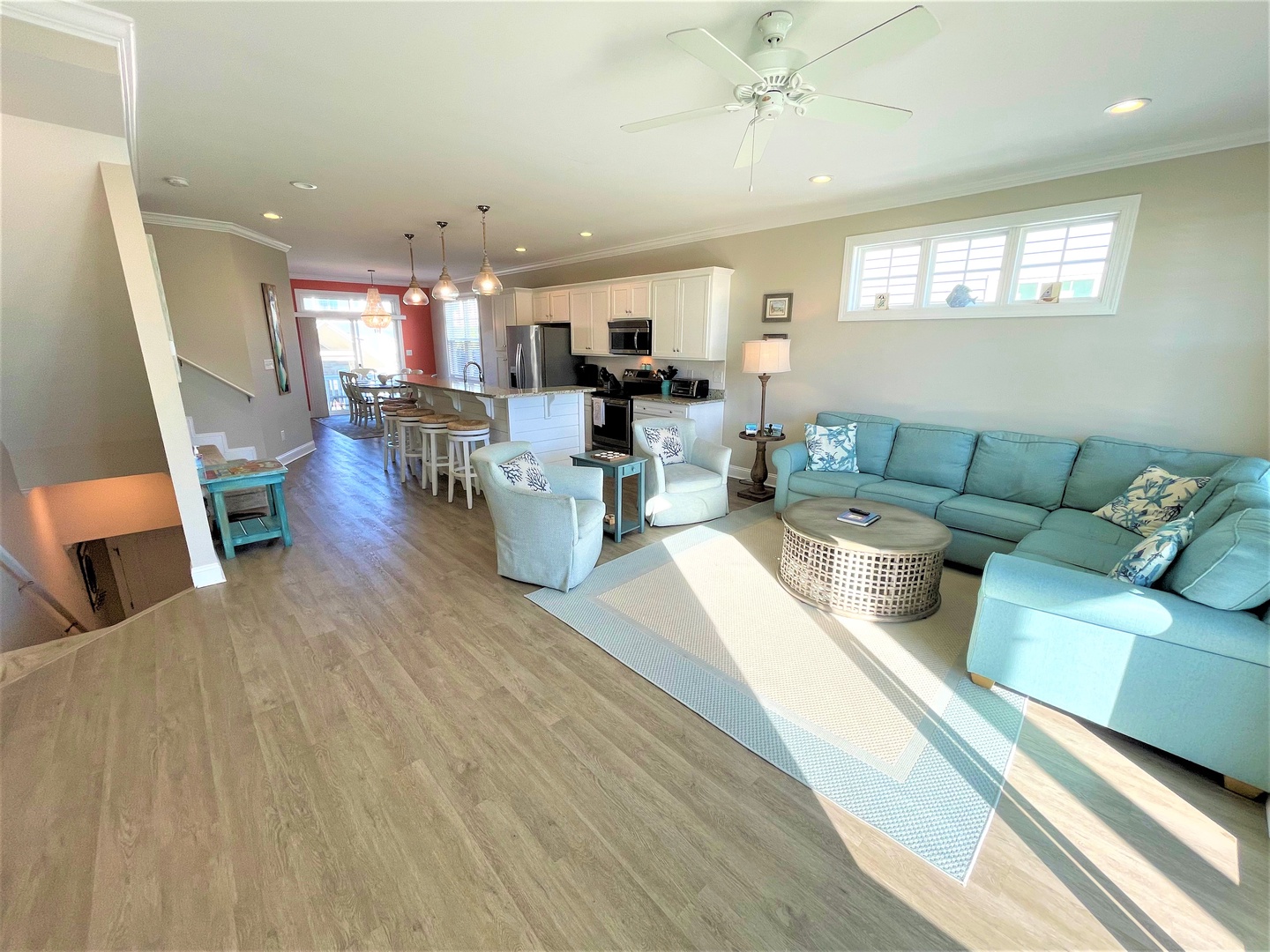 Relax in your spacious open-concept living area with a plush turquoise sectional, modern kitchen island, and beautiful natural light flowing throughout.
