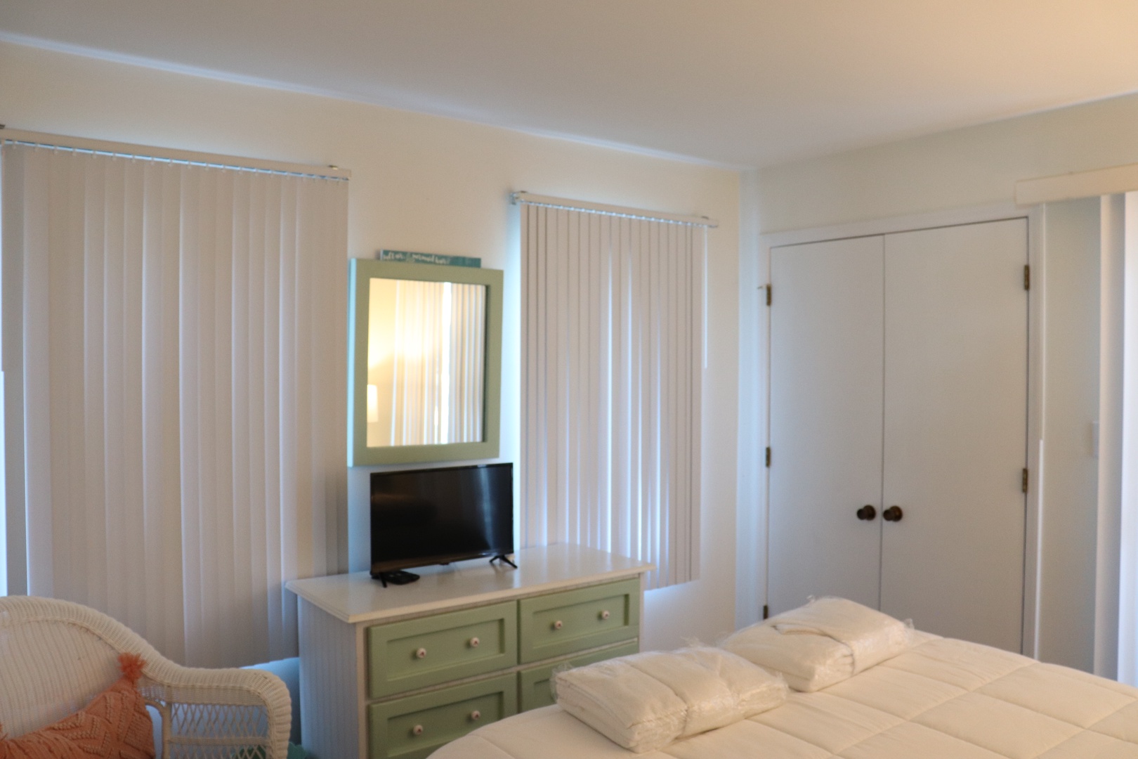 Your cozy bedroom features soft linens, charming mint dresser, flat-screen TV, and peaceful window views for ultimate relaxation.