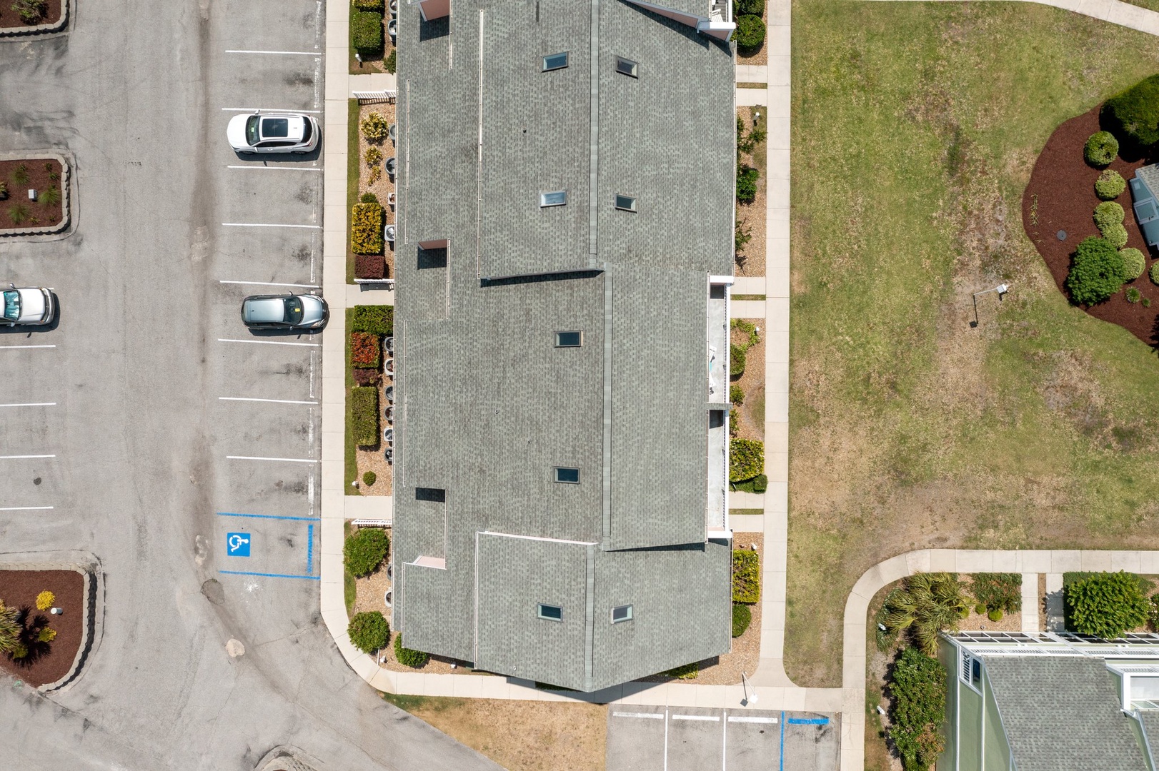 Aerial view of a modern property building with distinctive roofline and convenient parking adjacent to green spaces.