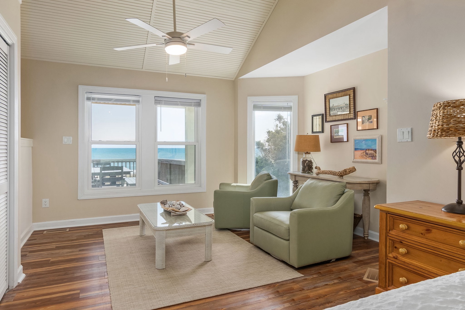 Unwind in your coastal retreat with ocean views through large windows, comfortable seating, and warm wood floors beneath soaring ceilings.