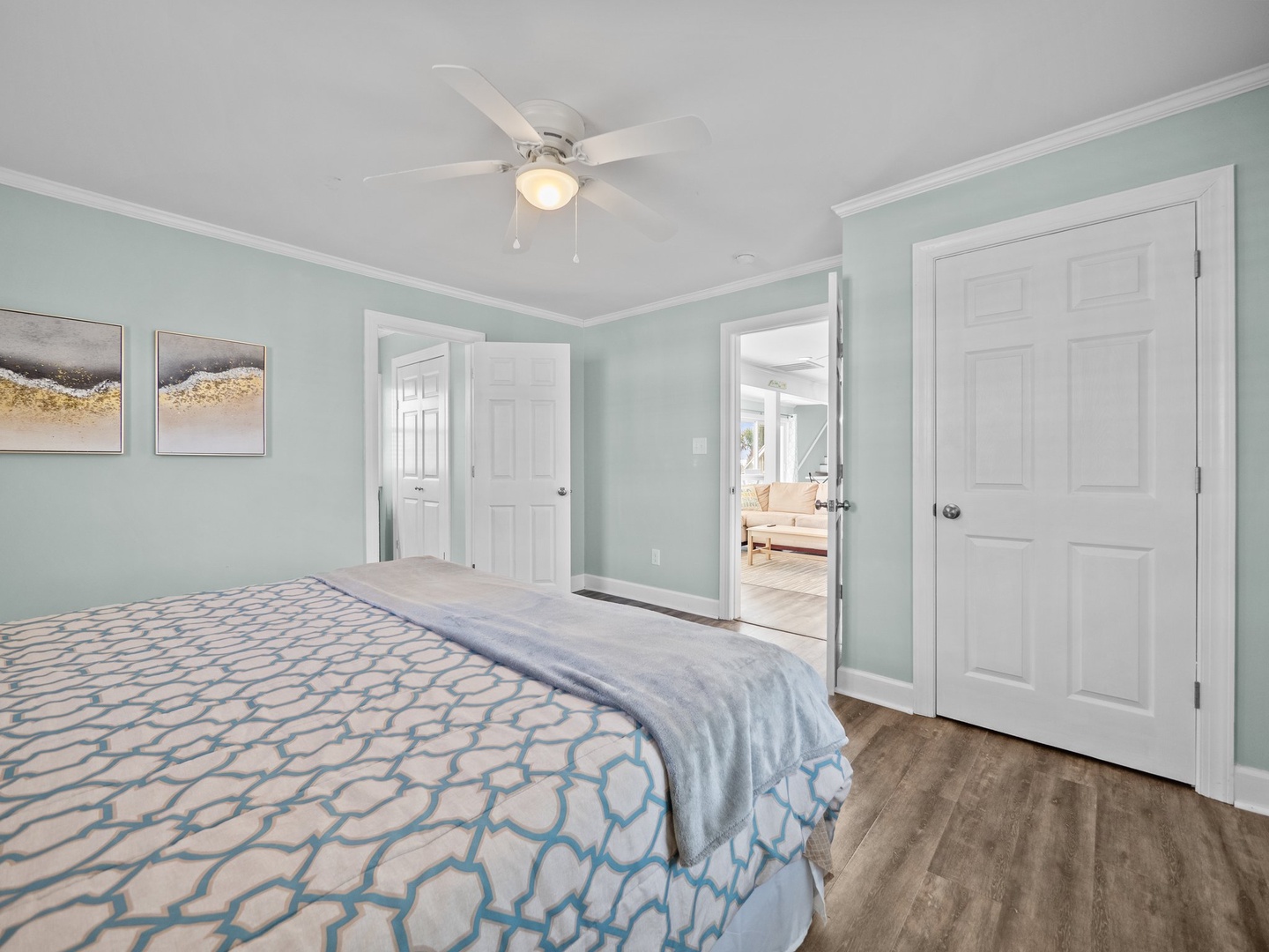 Drift off in your peaceful bedroom with soothing mint walls, cozy patterned bedding, and gentle ceiling fan for perfect comfort.